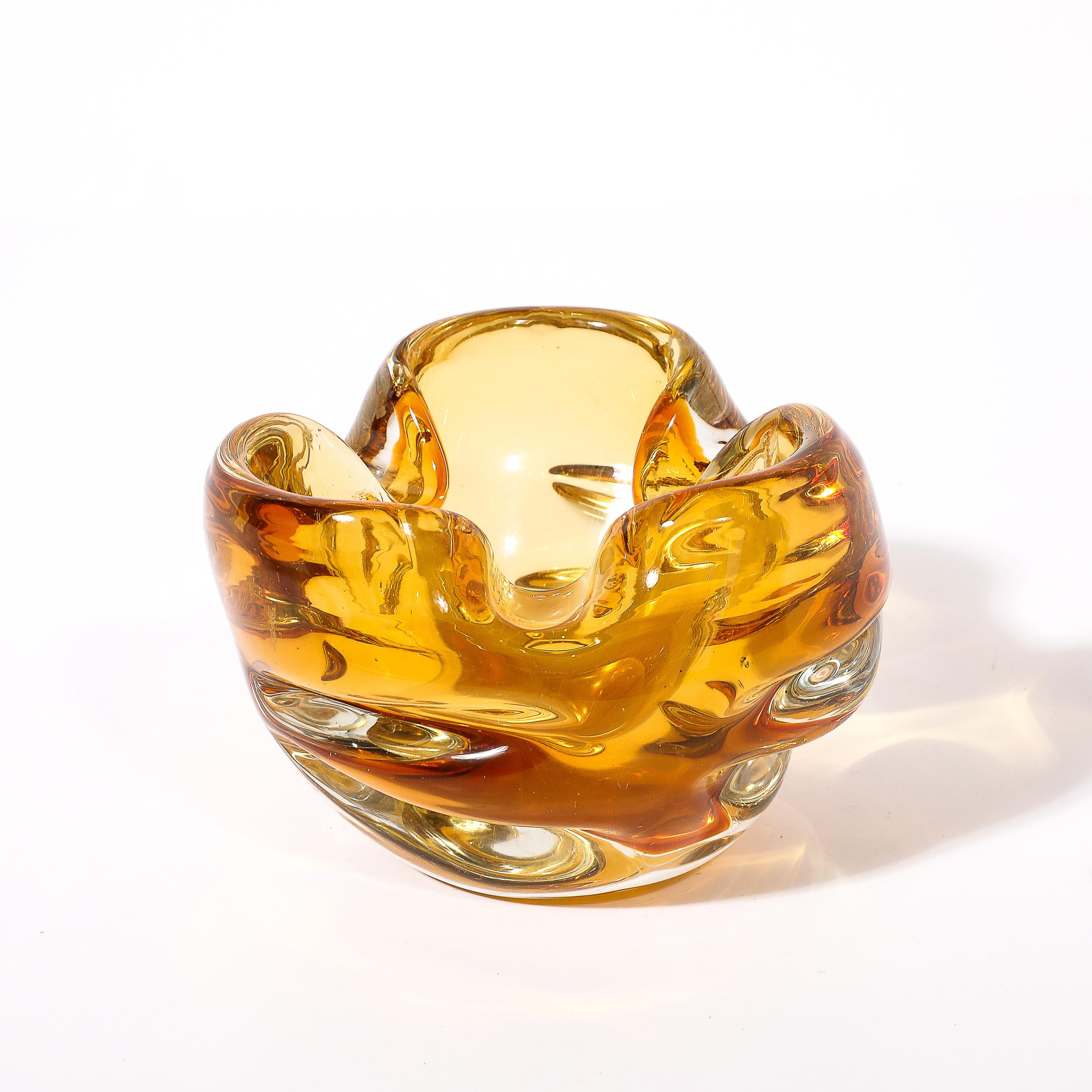 This elegantly formed and organic Mid-Century Modernist Hand-Blown Murano Glass Dish with Indented Detailing in Amber originates from Italy, Circa 1960. Features a beautiful expansion and contraction achieved by the ripples in the edge from three