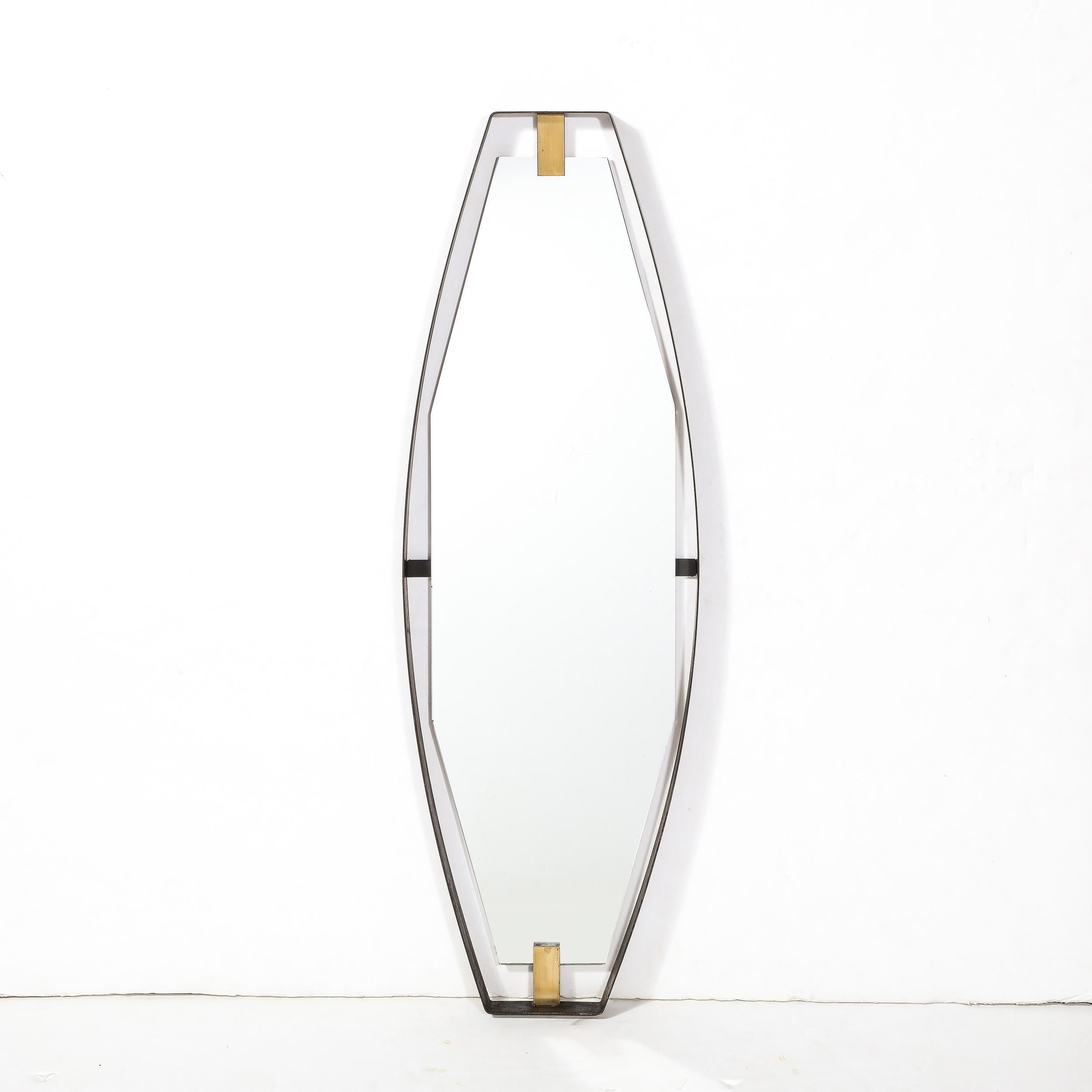 This Mid-Century Modernist Mirror in Black Enameled Bronze with Brushed Brass fittings originates from the United States, Circa 1950. Featuring an vertical oval form with cut angular top and bottom, this piece when hung vertically resembles the iris