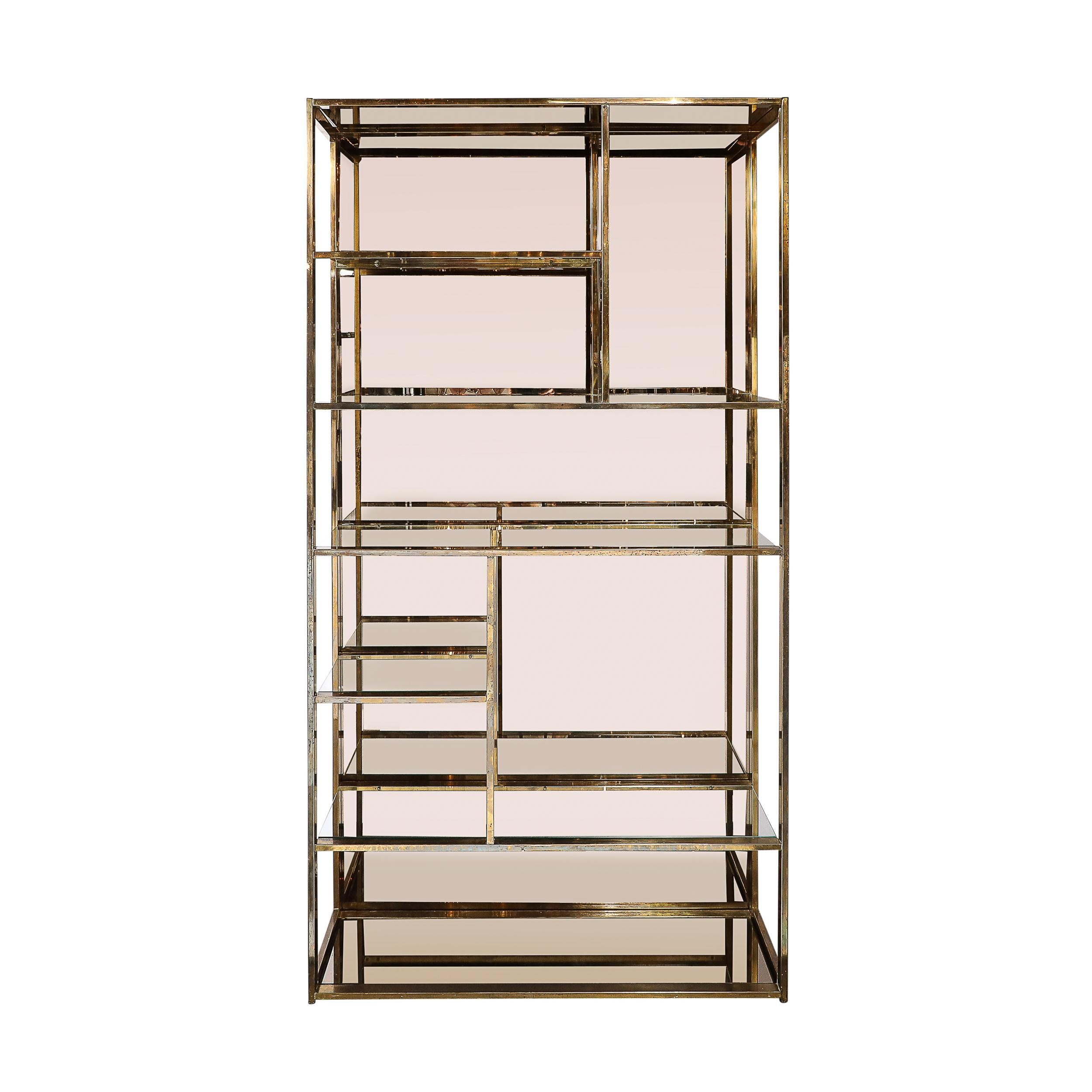 This sleek and well composed Mid-Century Modernist Étagère in Brass, Glass and Bronzed Mirror by Milo Baughman originates from the United States, Circa 1970. Features a patinated brass framework in rectangular elements that are joined at unique