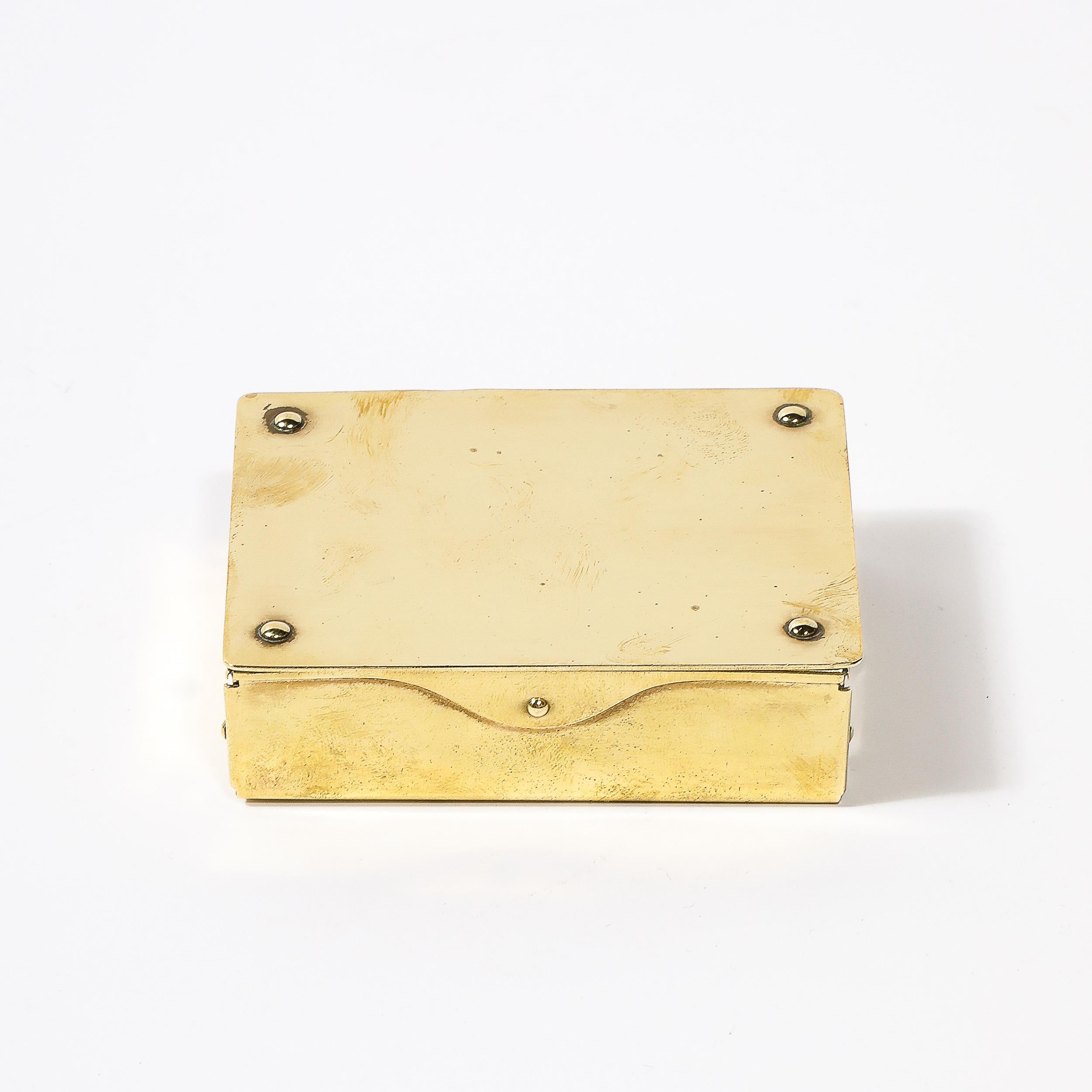 This beautifully made Mid-Century Modernist Brass Trinket Box W/Rivet Detailing originates from Germany, Circa 1950. Features a rectilinear composition with subtly curved edges and rivet detailing on the four corners of the top. Remarkably sturdy