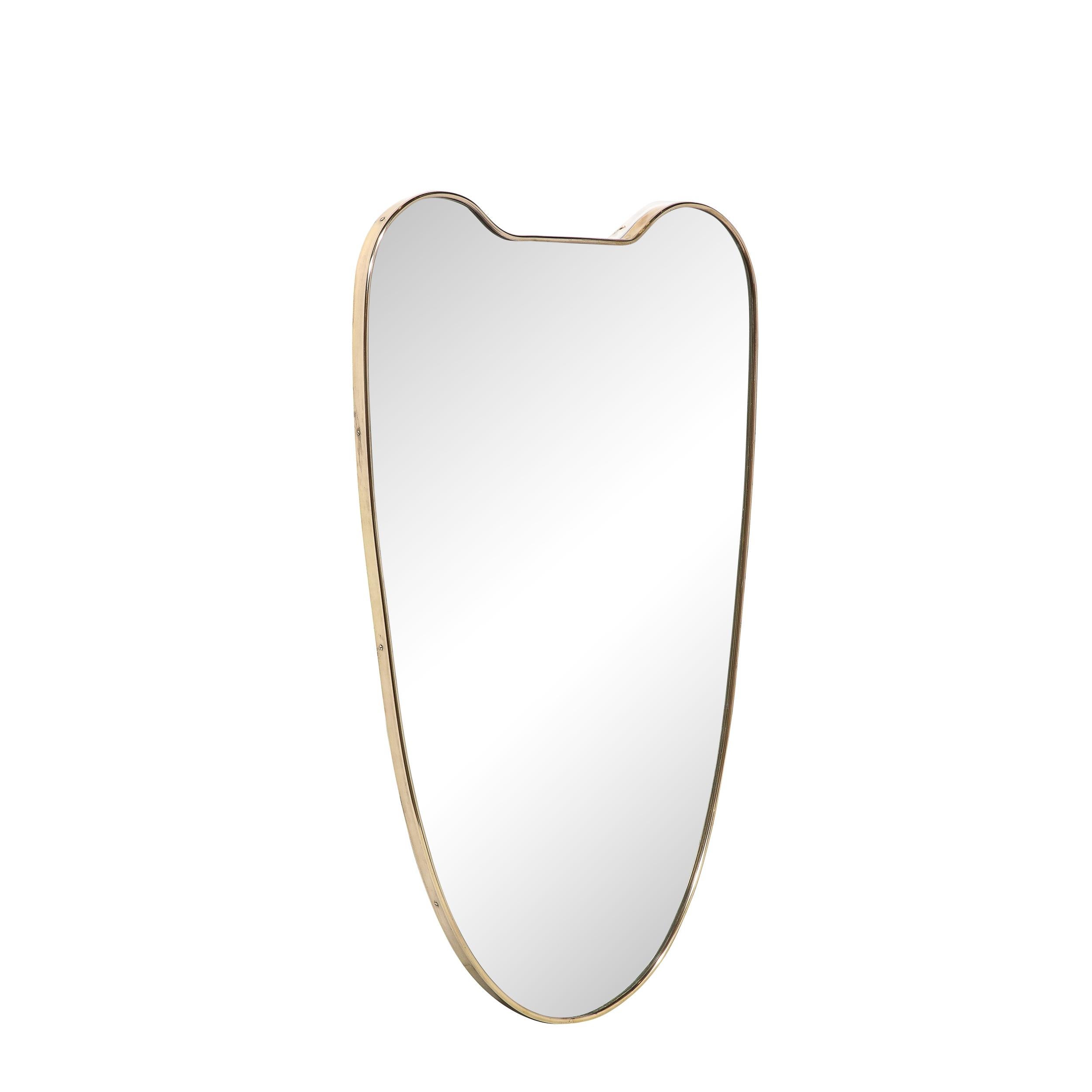 This minimal and beautifully made Mid-Century Modernist Brass Wrapped Shield Form Mirror originates from Italy, Circa 1960. Features a stunning heraldic shield form silhouette with rounded top corners and a beautifully curved lower section.
