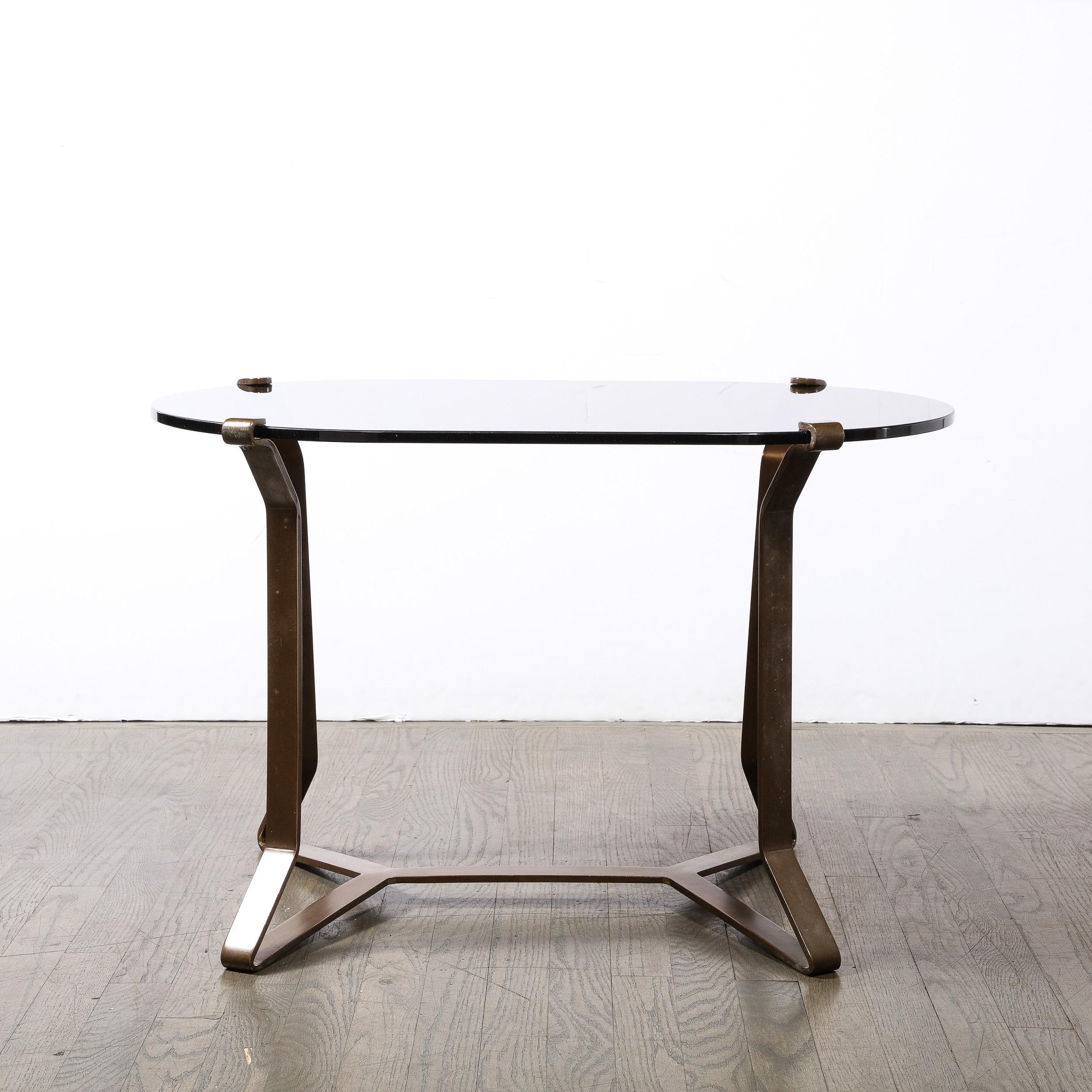 This dynamic yet reserved Mid-Century Modernist Bronze and Smoked Glass Cocktail / occasional Table originates from the United States, Circa 1950. Features supports and base composed of a minimal framework in bronze, elegantly formed and bent,