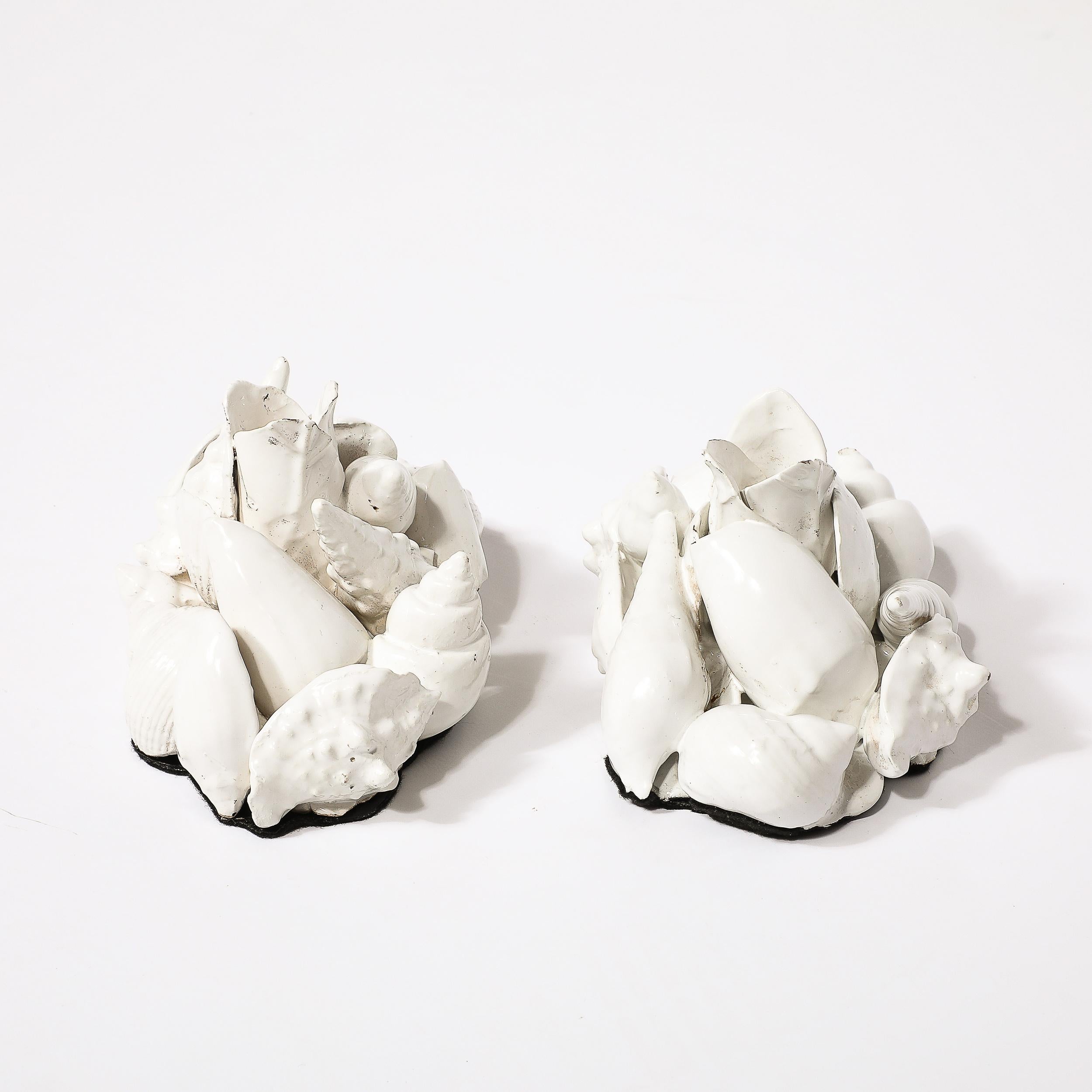 Cette élégante paire de bougeoirs en céramique de style moderniste du milieu du siècle en forme de coquillage provient d'Italie au cours du 20e siècle. Ils présentent une composition de coquillages en grappe, disposés de manière organique et