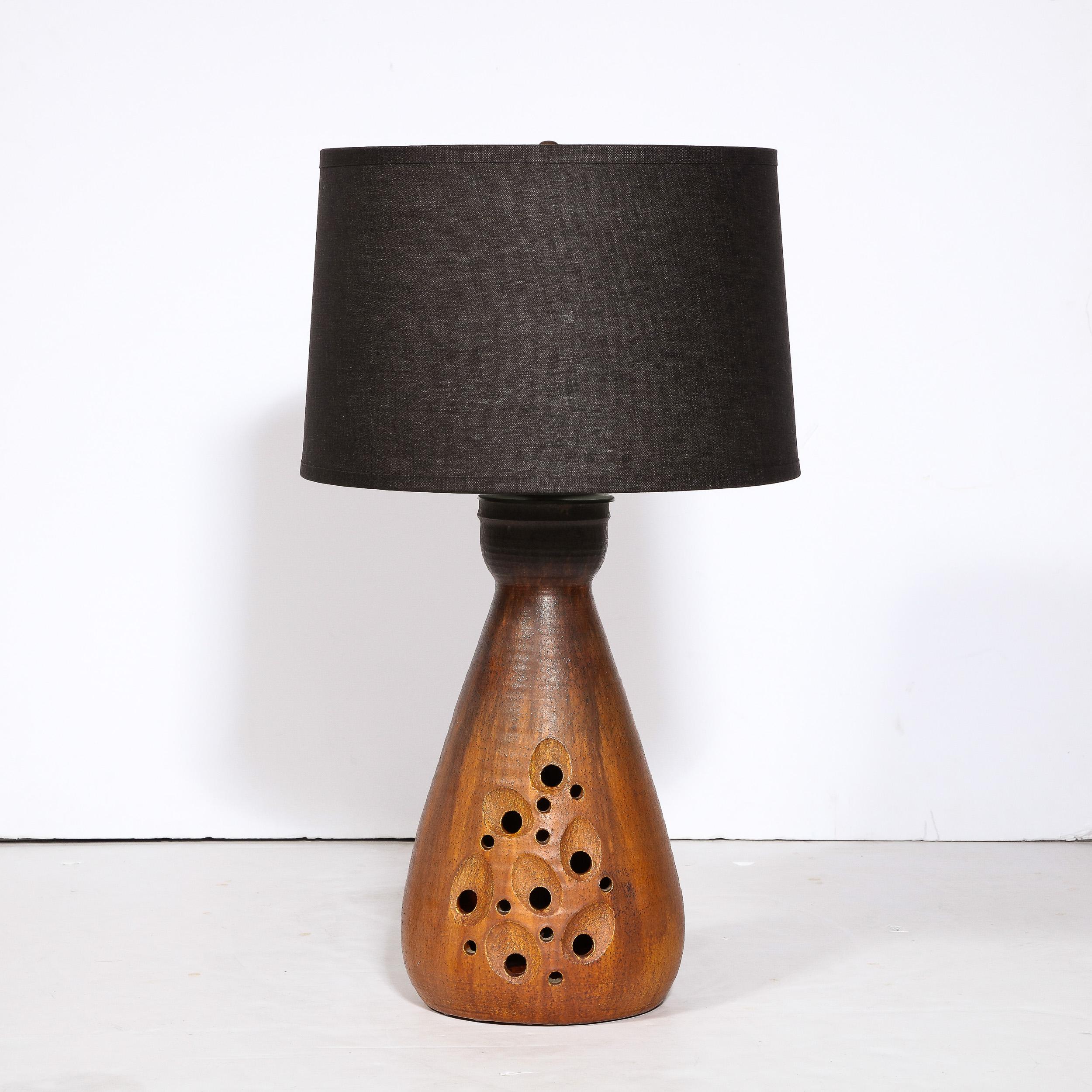 This elegant and sophisticated Mid-Century Modern ceramic table lamp was realized in France, circa 1960. It features a tear drop form realized in a red oxide glaze that transitions in a sophisticated gradient to a slate at the flared neck. The top