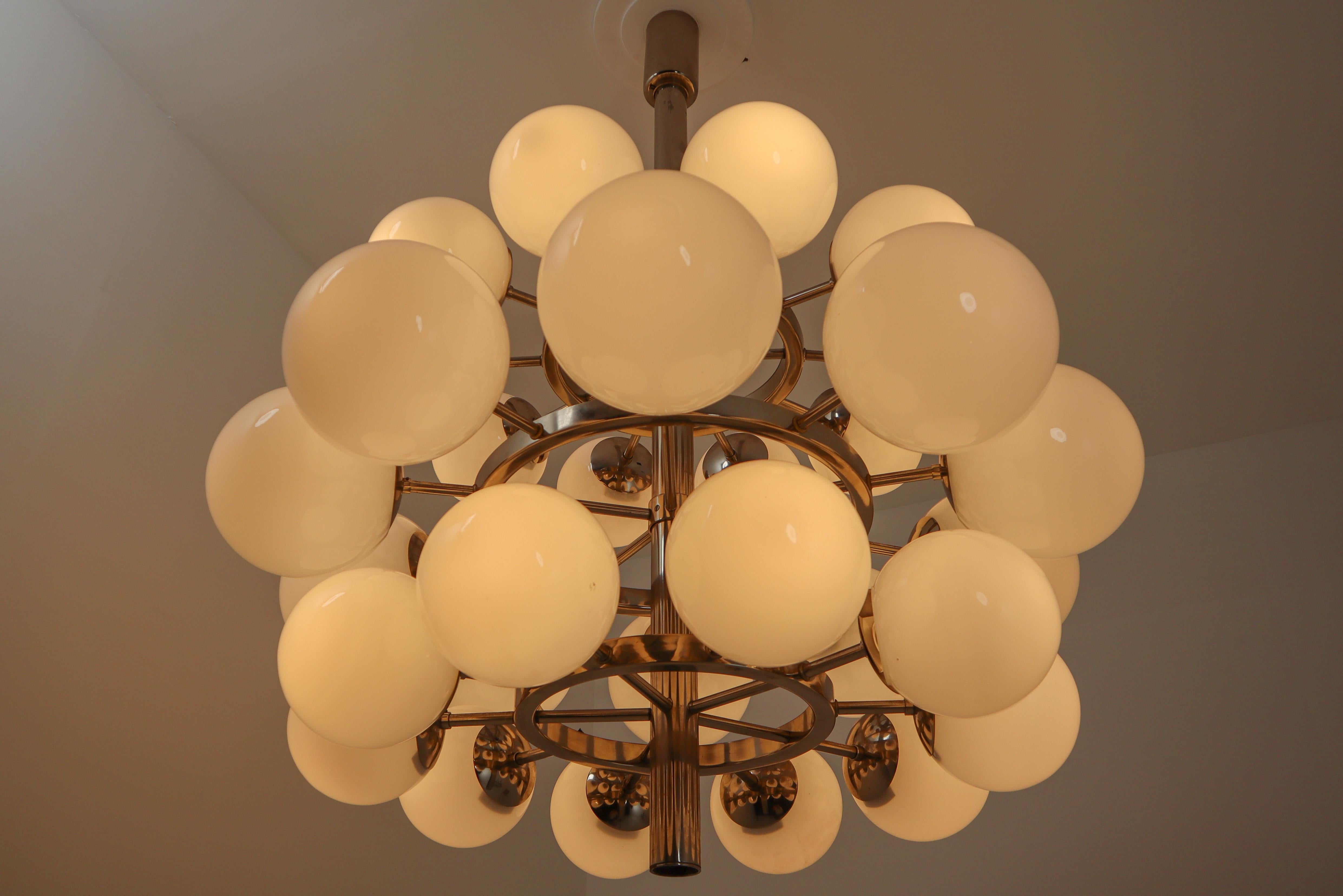 A midcentury modernist large chandelier with 30 handblown opaline glass globes. The fixture is made of metal with a chrome-brass patina. Therefore an attractive color is visible on the metal. Thirty opaline glass globes are placed over three levels.