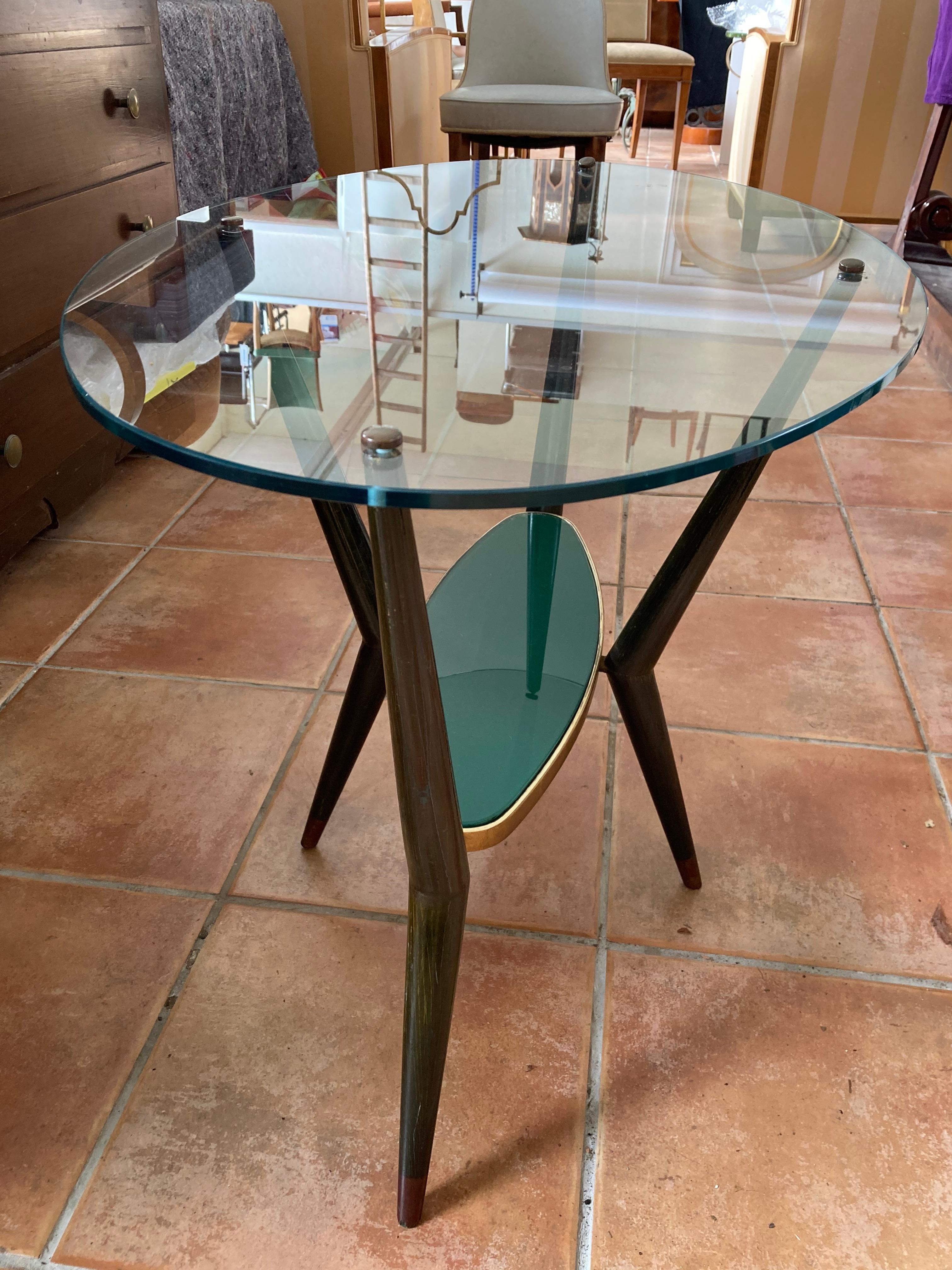 Rare oval Italian Modernist cocktail table in the style of Cesare Lacca.
Oval upper glass top.
Conical green and red patinated wooden legs.
The lower small green glass top is inlaid .
The upper glass top is screwed on the wooden frame and has small