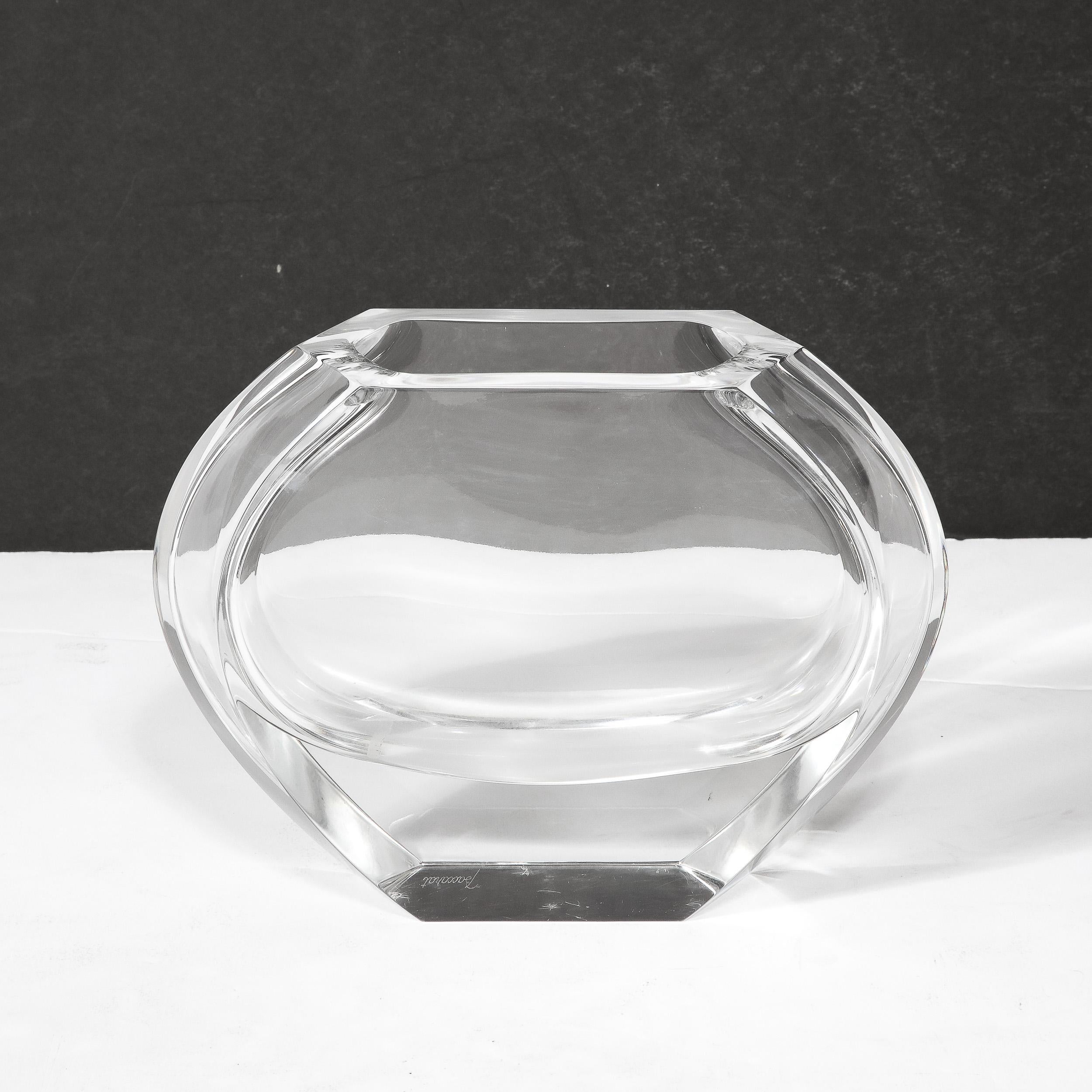 This Mid-Century Modernist Crystal Vase by the esteemed glass manufacturer Baccarat originates from France, Circa 1960. Composed of walls of transparent crystal that lead to a substantially thick and prismatic base, the outer edges of the curved
