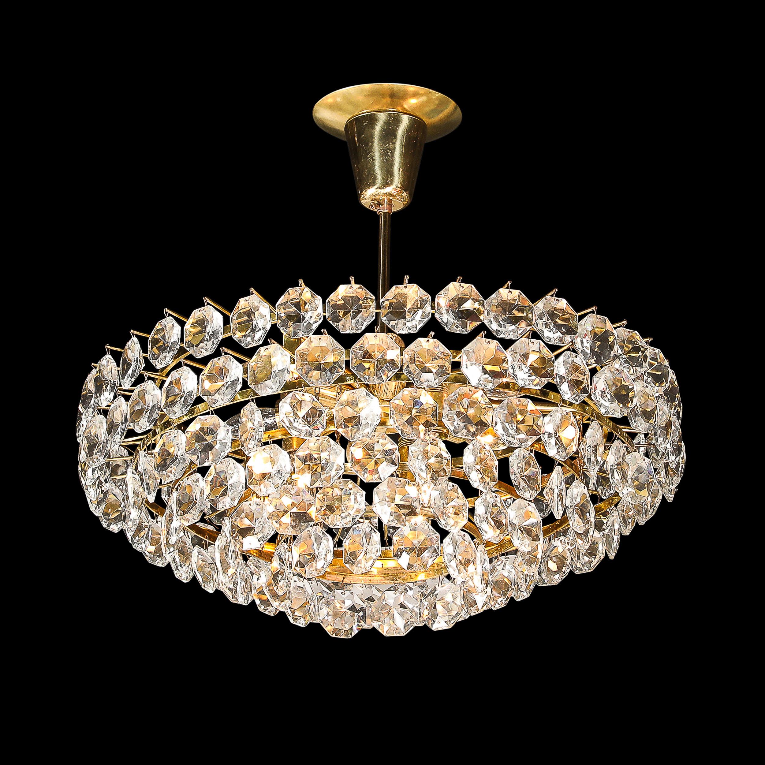 This Mid-Century Modernist Crystal and Polished Brass Pendant Chandelier by Bakalowits and Sohne originates from Austria, Circa 1960. This pendant is a well adorned and elegant fixture, featuring a polished brass canopy, rod, and frame supporting