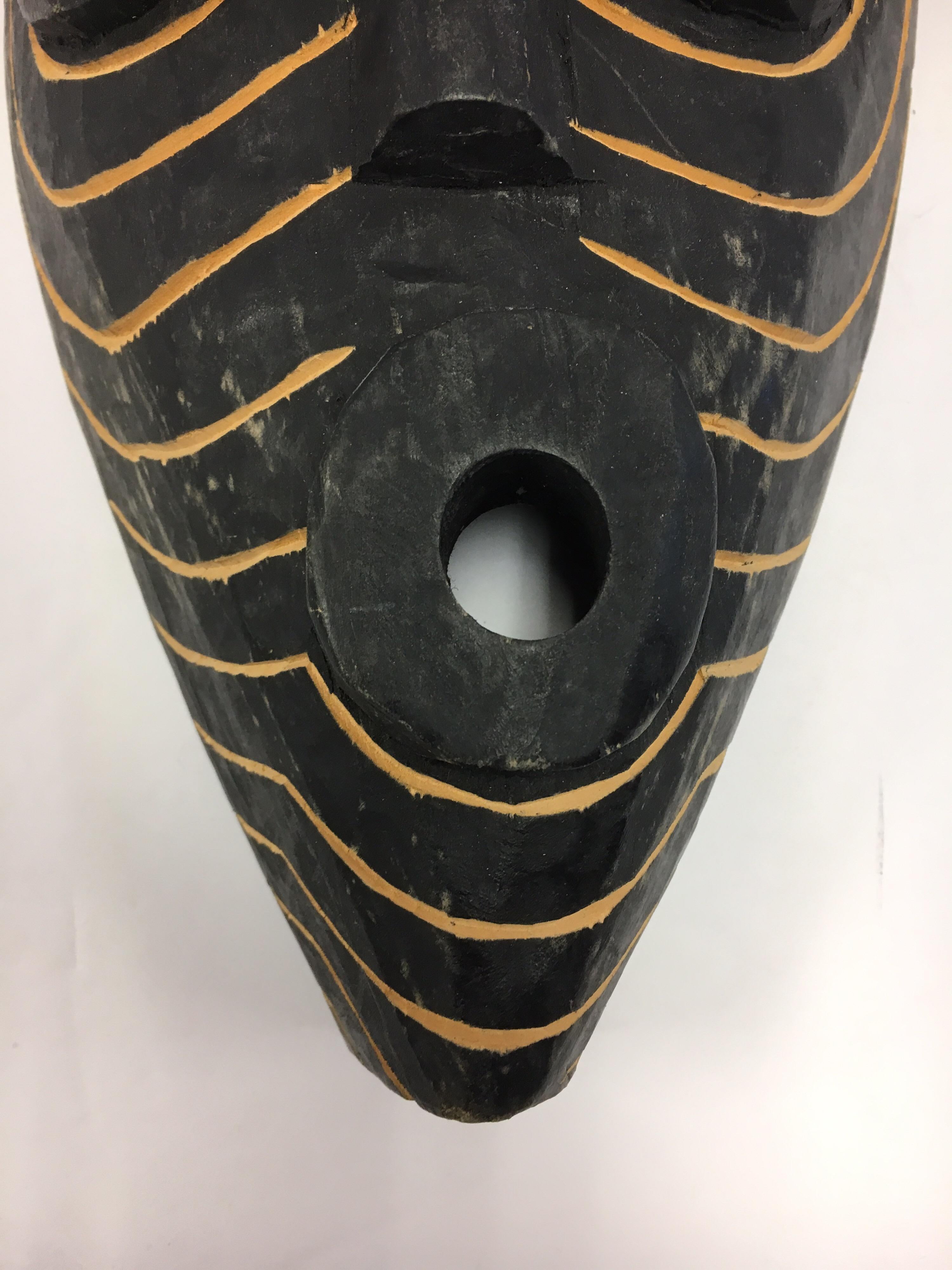 Coveted decorative African hand-carved wood mask with graphic elements, circa 1960s.
This is a decorative item from the 1960s, it was made for export, it is not an antique tribal mask.
It was made by a master carver from a single piece of wood and