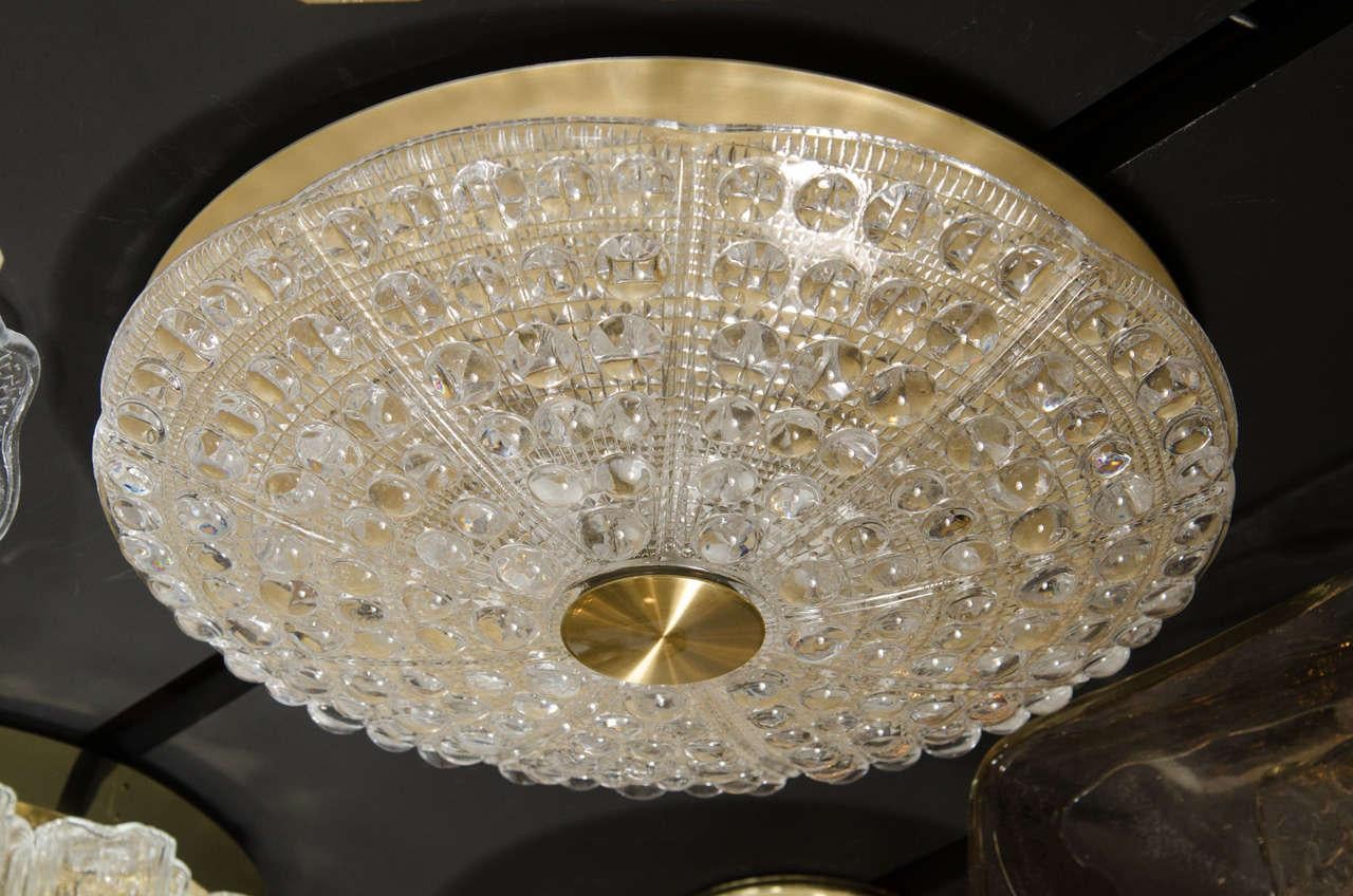 Mid-Century Modernist flush mount chandelier by Carl Fagerlund for Orrefors. This flush mount features a stunning pressed glass dome with a slight scalloped top that has accentuated lines that emanate from its brass centerpiece. The pressed glass