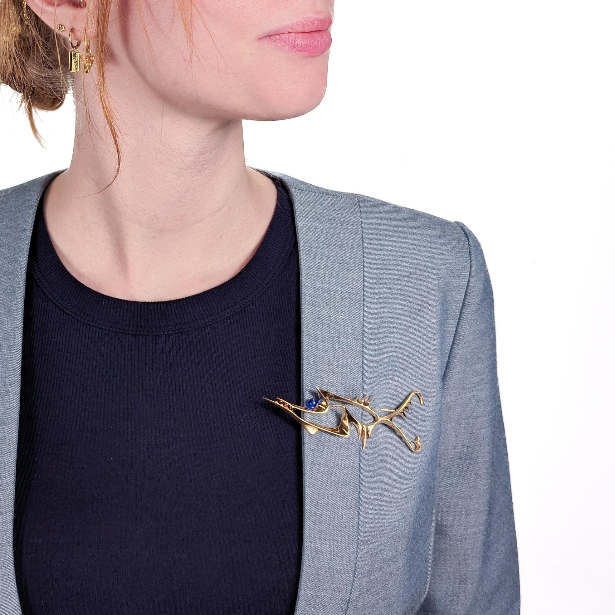 A fine Modernist brooch by Ronald Hayes Pearson.

In 14-karat forged yellow gold with a post-set round blue topaz gemstone bead.
  
Ronald Pearson is an extremely important figure in the 20th Century American Craft movement. 

Together with John
