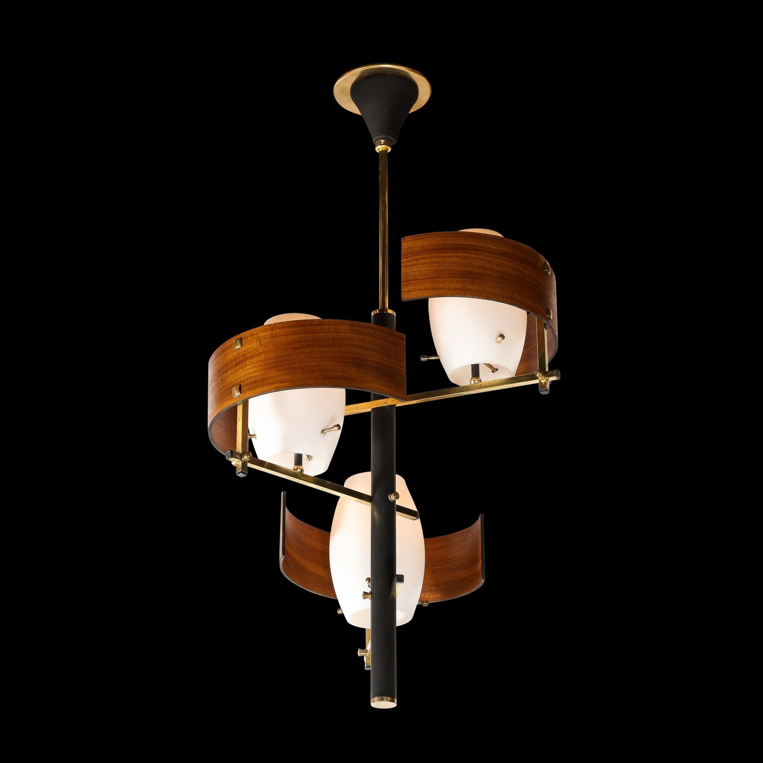 This elegant Mid-Century Modern pendant was realized in France circa 1960. It features three volumetric ovoid shades in a matte milk glass pierced through with cylindrical brass supports near their bases. The shades are affixed to brass arms that
