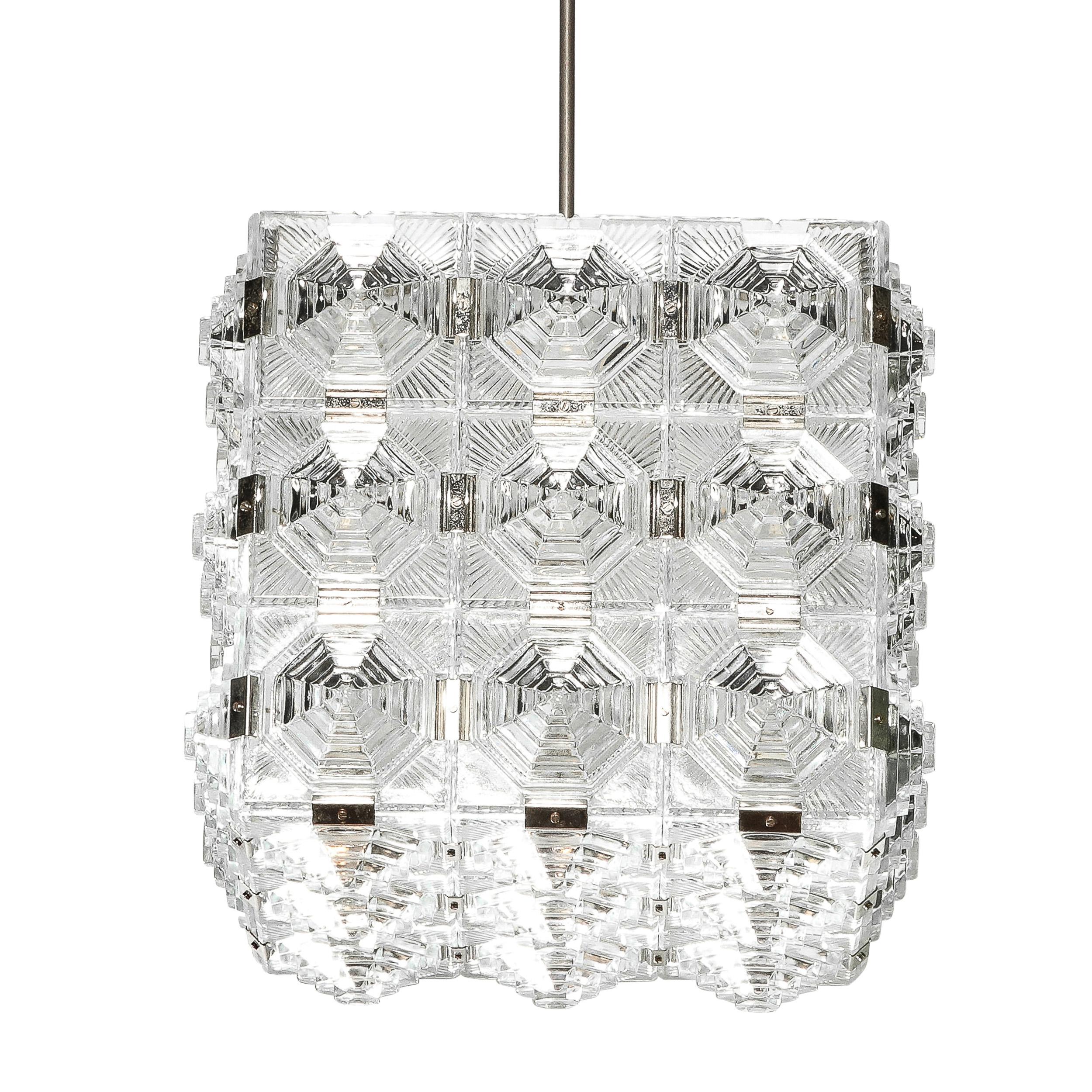 This pair of Mid-Century Modernist Square Pendant Chandeliers were created by the esteemed maker Kinkeldey and originate from Germany, Circa 1970. Composed in repeating skyscraper style tiered pressed glass shades connected edge to edge with chrome