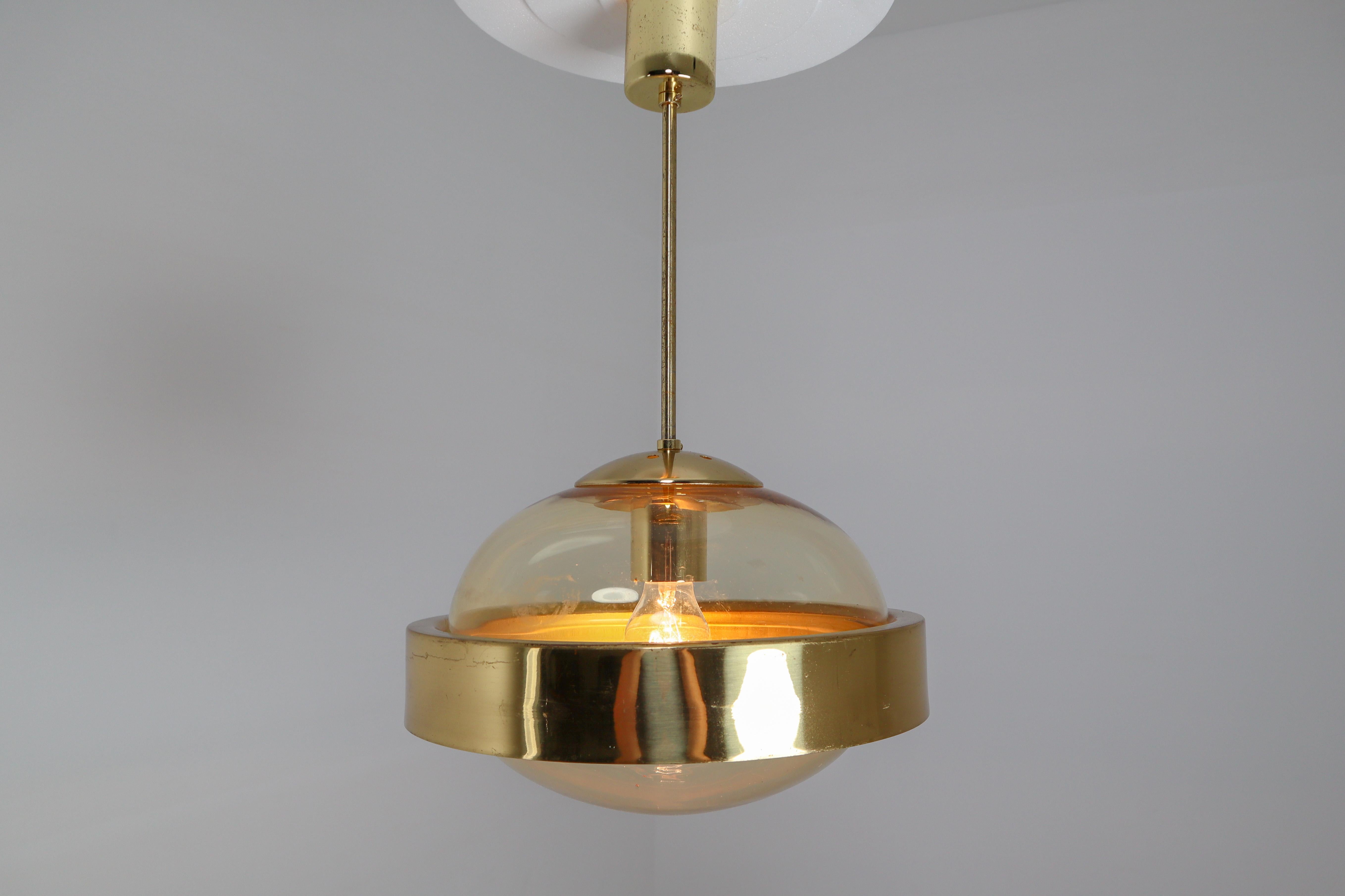Mid-Century Modernist brass and hand-blowed glass pendant, 1960s. The hand blown glass globe have a amber tint to them and contain air bubbles of varying sizes and density that create a wonderful light effect. This pendant will contribute to a