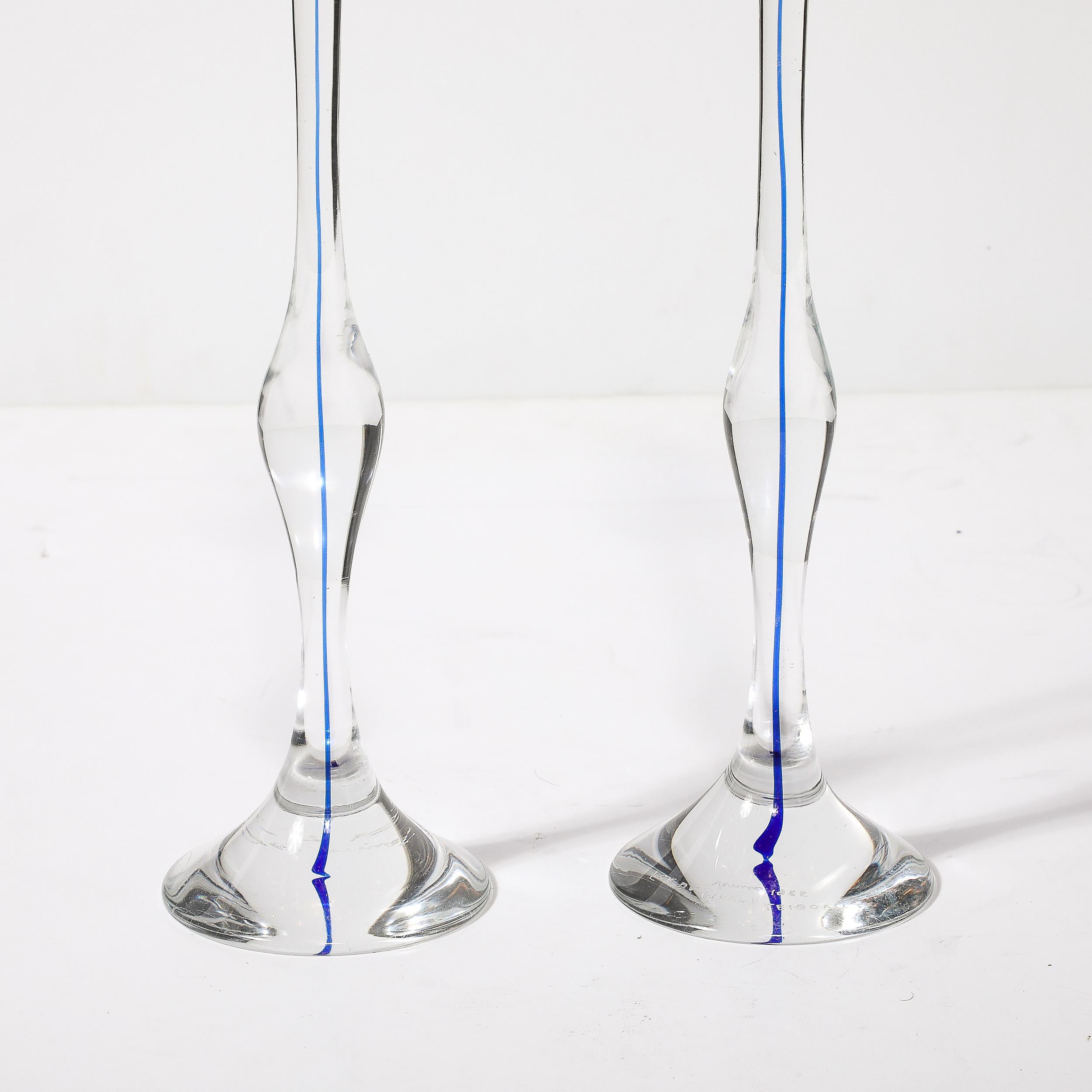 Cette étonnante paire de bougeoirs en verre clair et cobalt de Murano, soufflé à la main et de style moderniste du milieu du siècle, provient d'Italie, C.C. 1985. Cette paire se caractérise par une présence verticale élancée réalisée en verre de