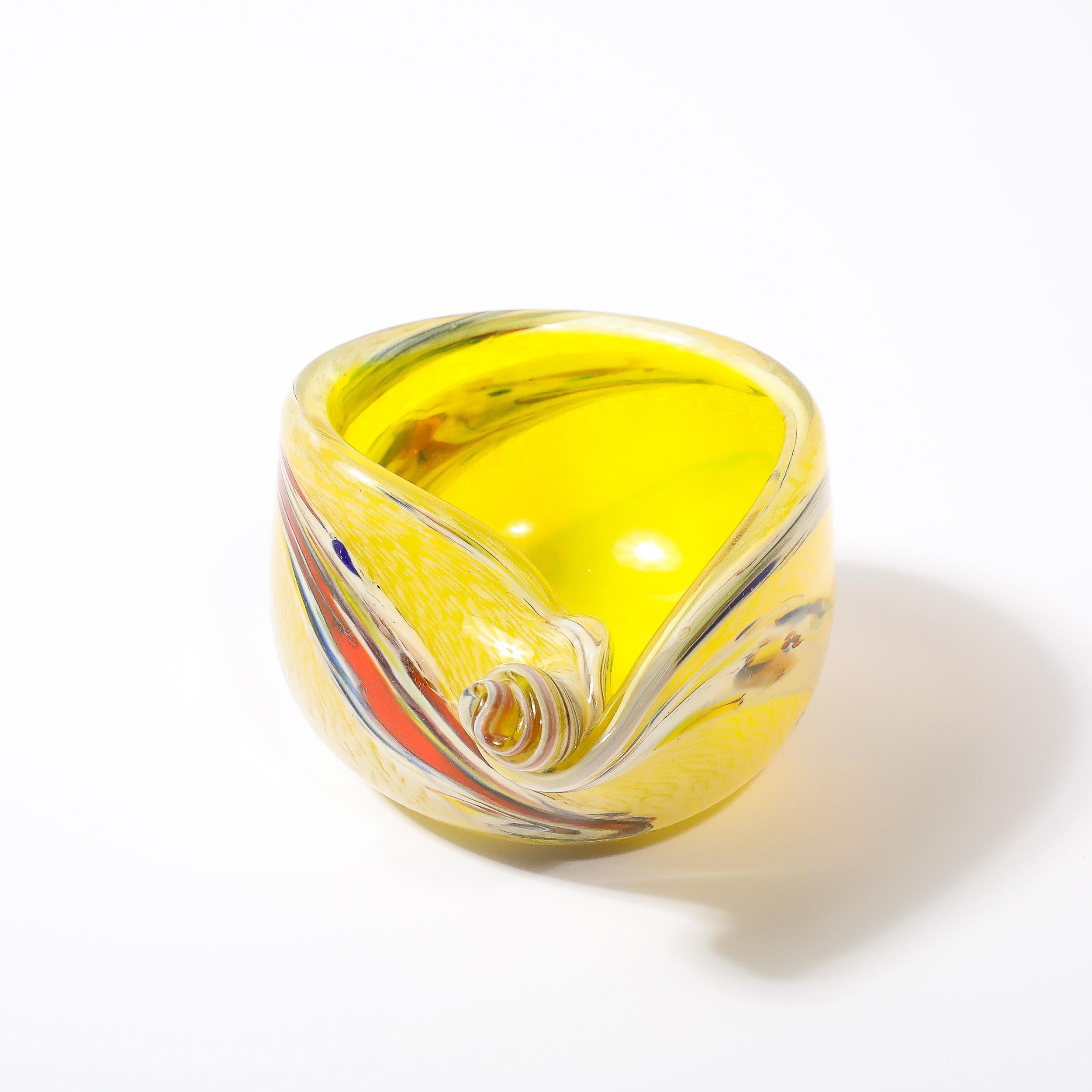 This lovely hued and elegantly achieved Mid-Century Modernist Hand-Blown Murano Glass Shell Form Bowl in Lemon Yellow with Striated Detailing originates from Italy, Circa 1960. Features a shell form profile with an asymmetrical spiraled twist detail