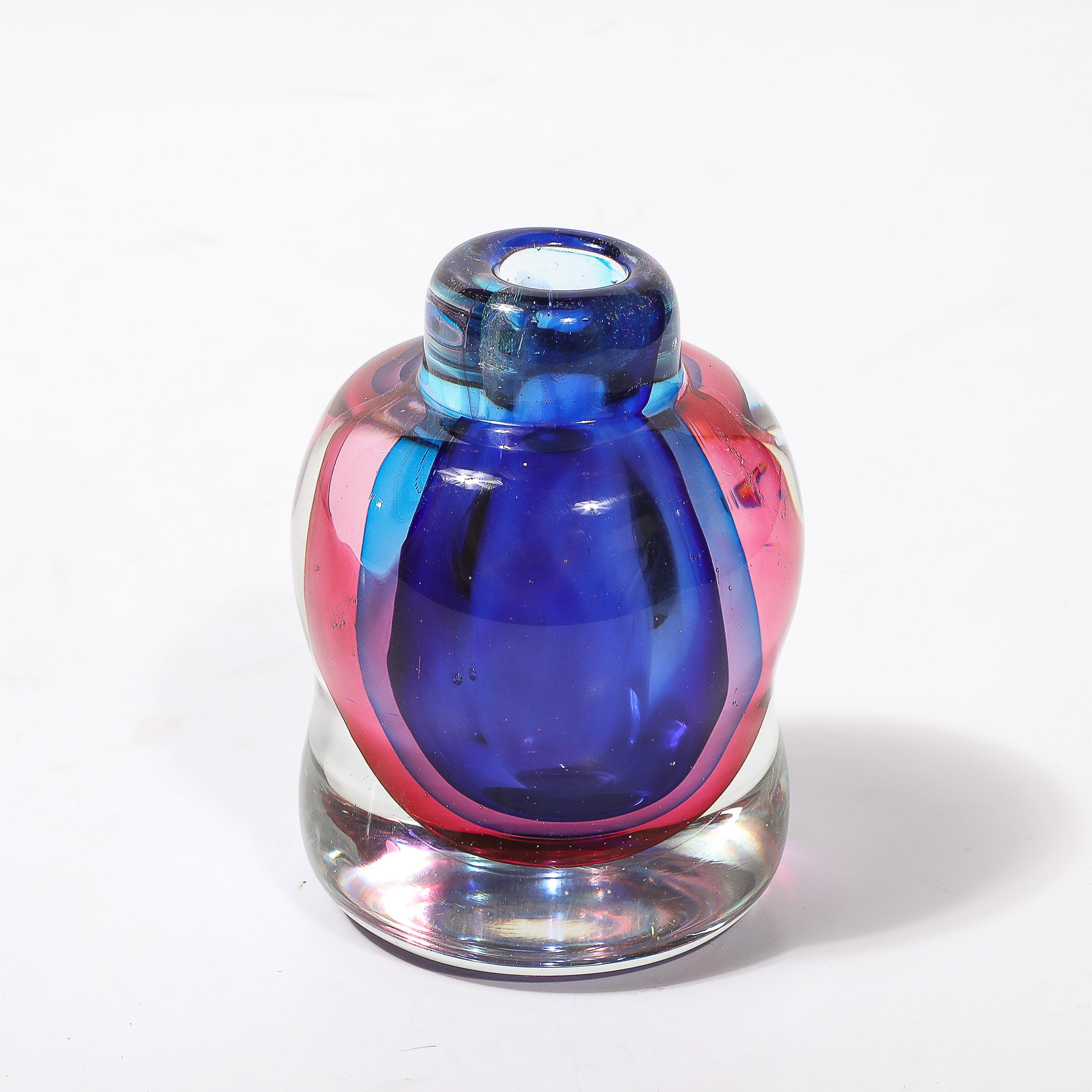 Cet exquis vase moderniste du milieu du siècle, soufflé à la main à Murano, en Italie, vers 1960, présente la technique sophistiquée du Sommerso, dans laquelle des couches de couleurs contrastées sont immergées dans du verre transparent. Ce