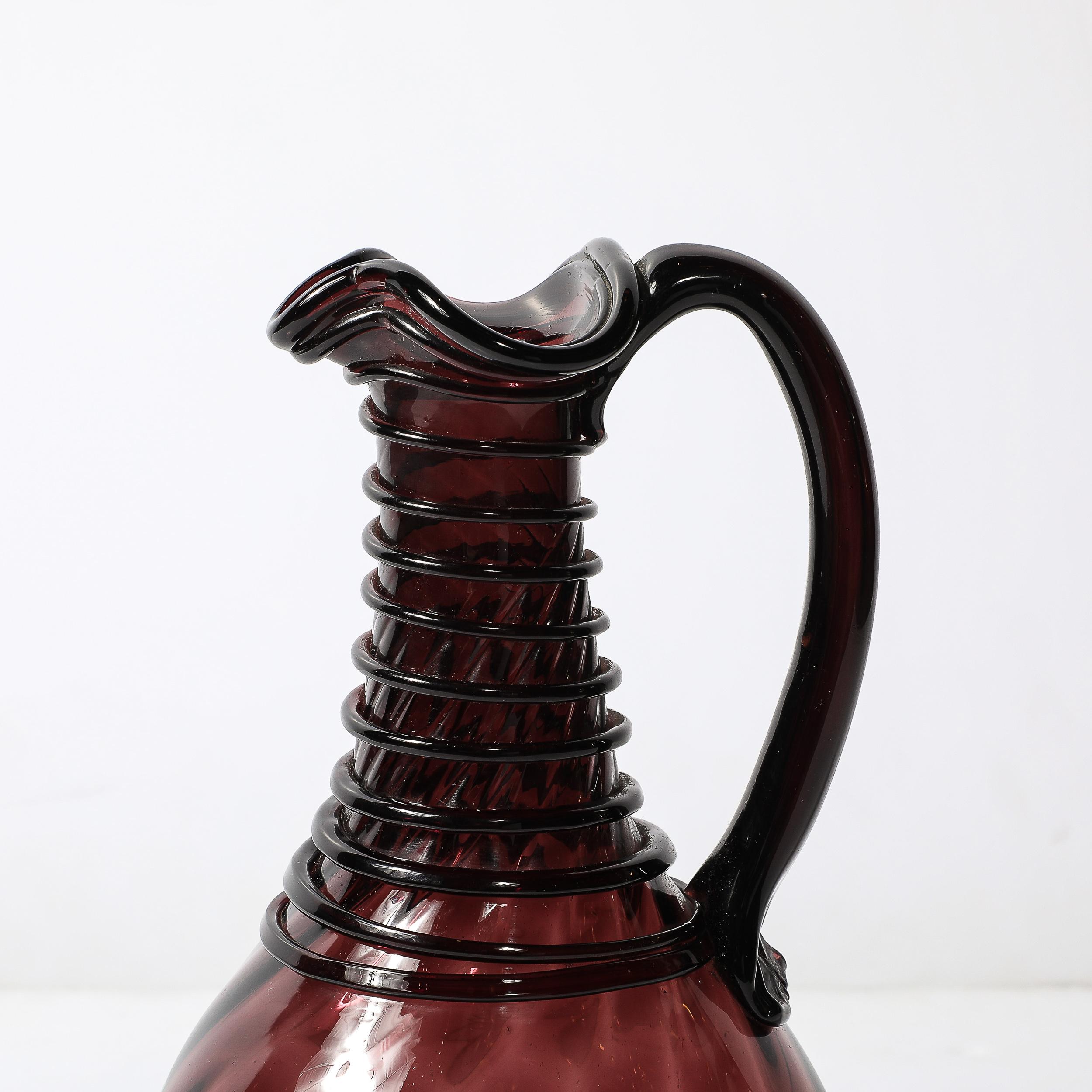 Ce pichet ludique en verre moderniste du milieu du siècle, soufflé à la main en Italie, vers 1960, dégage un caractère charmant et unique. Fabriqué en verre fumé améthyste de haute qualité, il capte la lumière avec une élégance subtile tout en