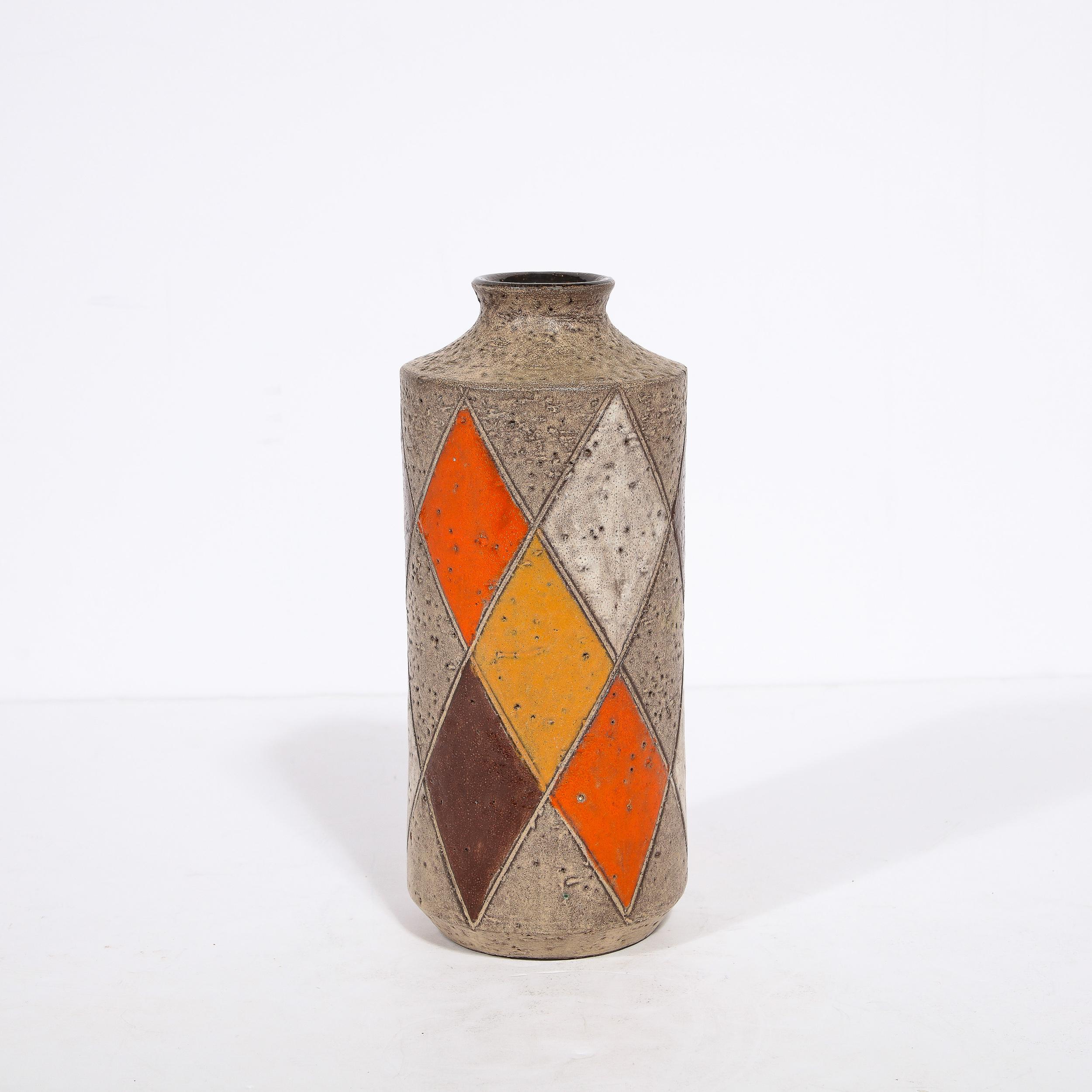 This refined Mid Century Modern ceramic vase was realized by the esteemed maker Thor in Denmark circa 1960. It offers a cylindrical body, and dramatically sloped shoulders that curve upwards to a truncated neck and round mouth- all in a beautiful
