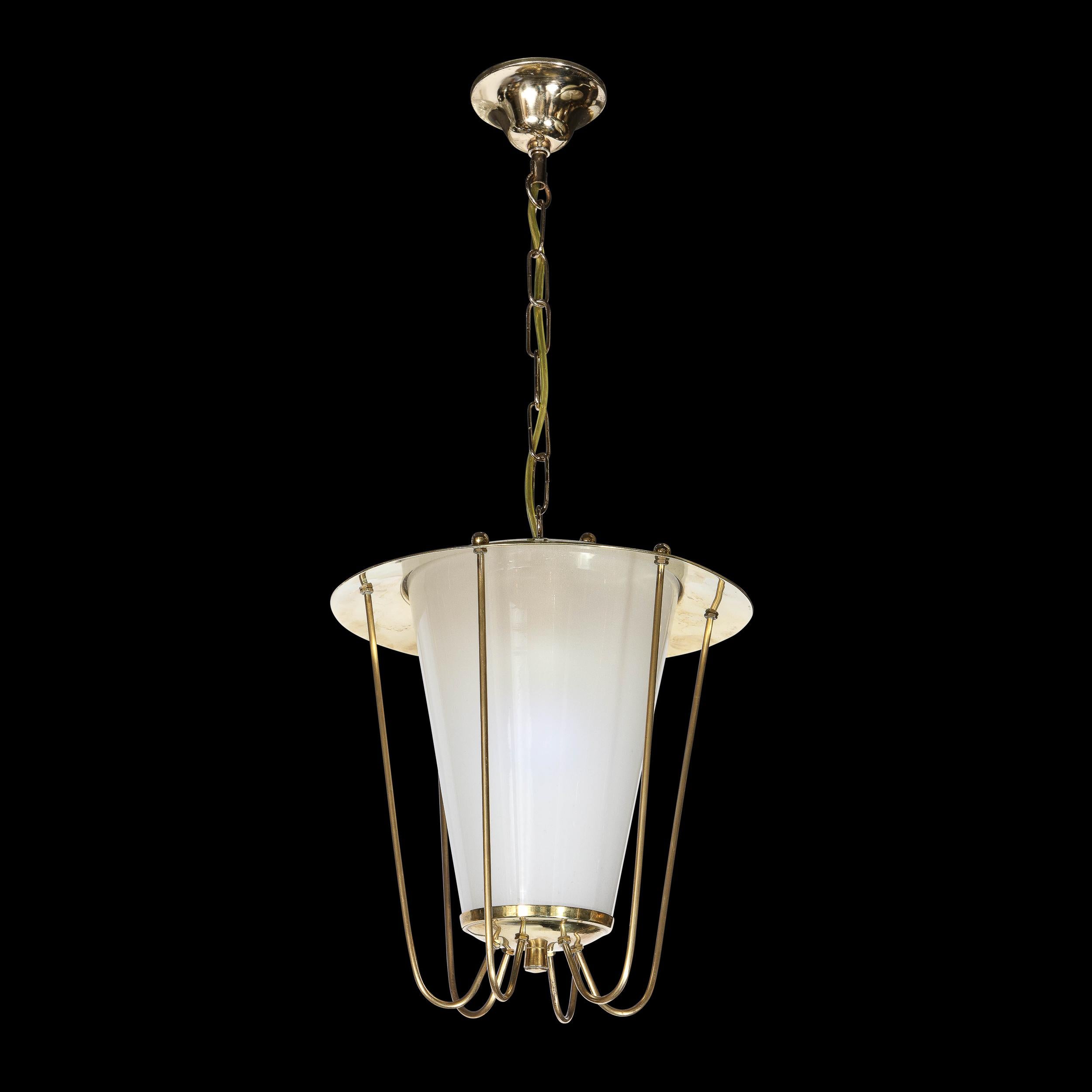 This elegant Mid Century Modern lantern chandelier was realized in Italy, circa 1960. It features a subtly conical shade in opaque white milk glass that is secured at its bottom by a subtly convex polished brass support capped with a cylindrical