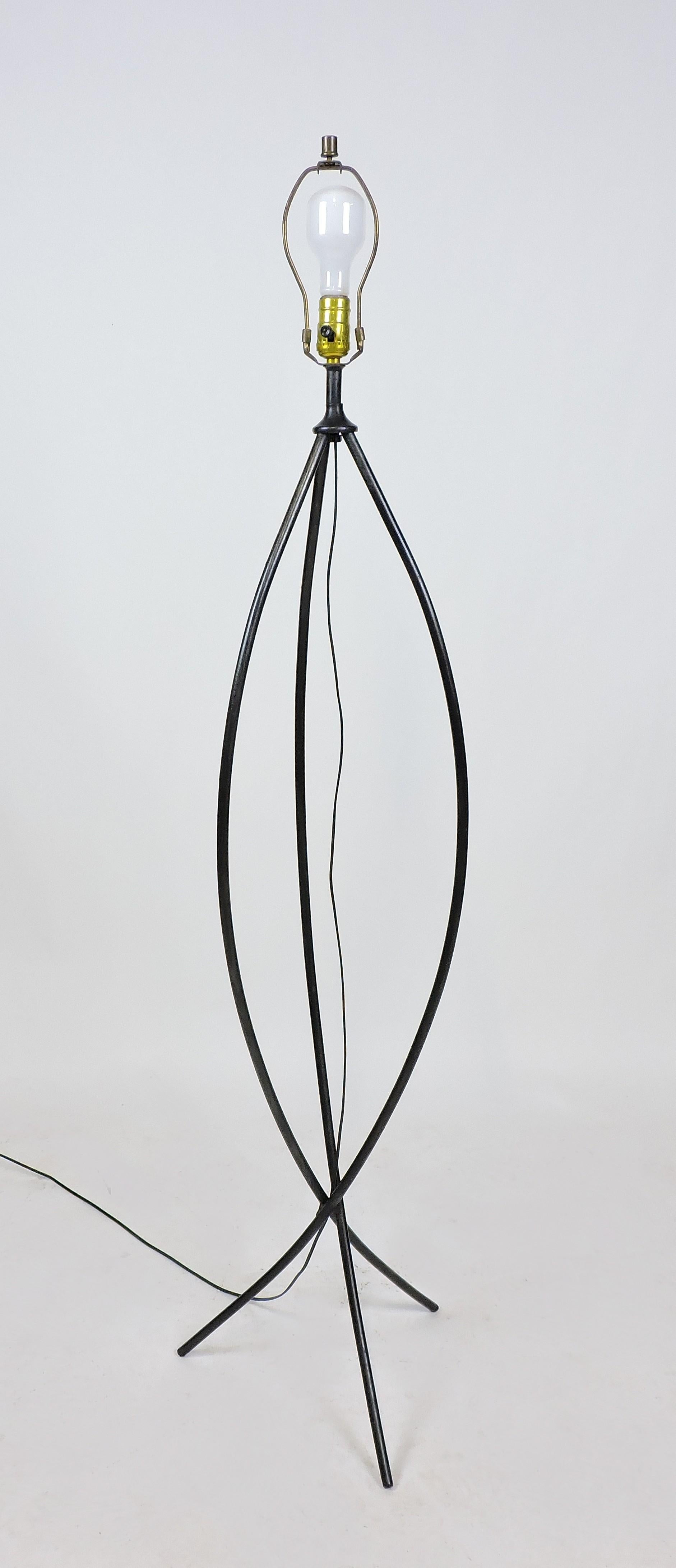 Modernist style tripod floor lamp. This lamp consists of three curved iron rods and has a very cool minimalist look. It takes a three-way bulb and has all new wiring. The shade is not included.