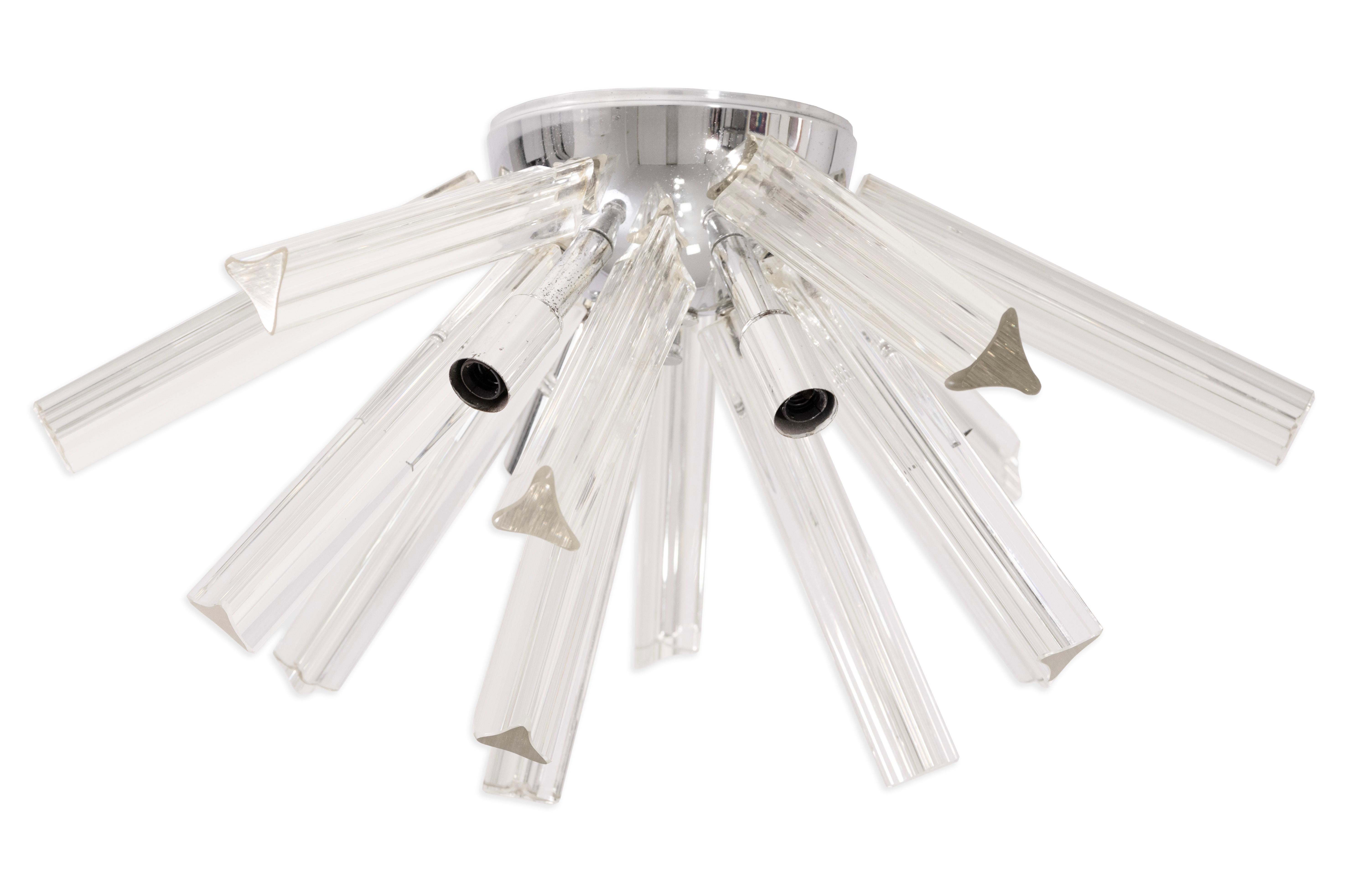 Esta llamativa lámpara de techo modernista de mediados de siglo presenta un conjunto de varillas de cristal de Murano soplado a mano que irradian desde una base de cromo pulido. Cada elemento de cristal se elabora con precisión, mostrando la