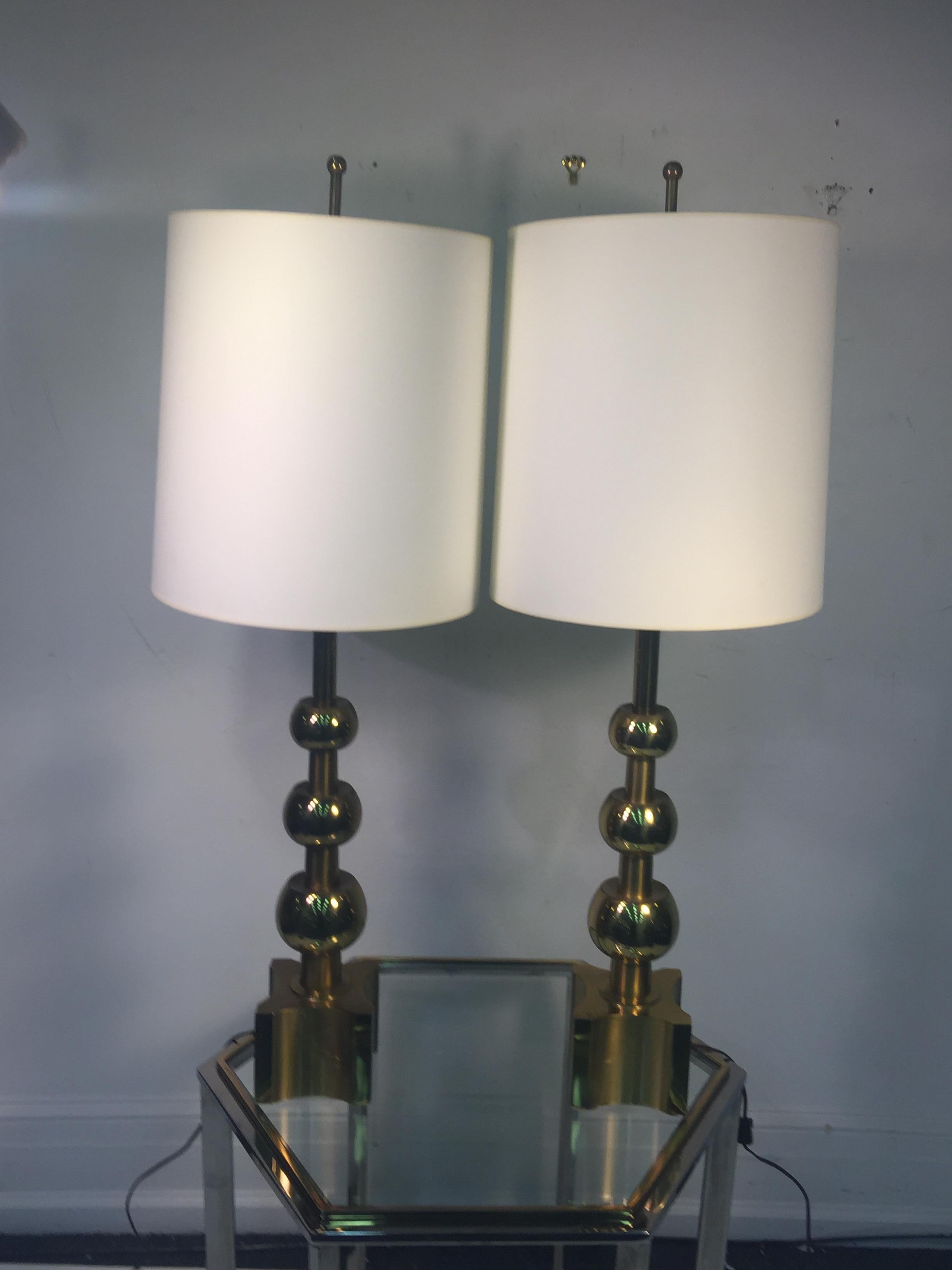 Elegant pair of modernist gold ball stacked lamps composed of gold plated metal and brass. Designed in the 1950s -1960's In The Manner Of Tommi Parzinger these have a great custom brass stick and ball finial. The lamp body alone without the harp