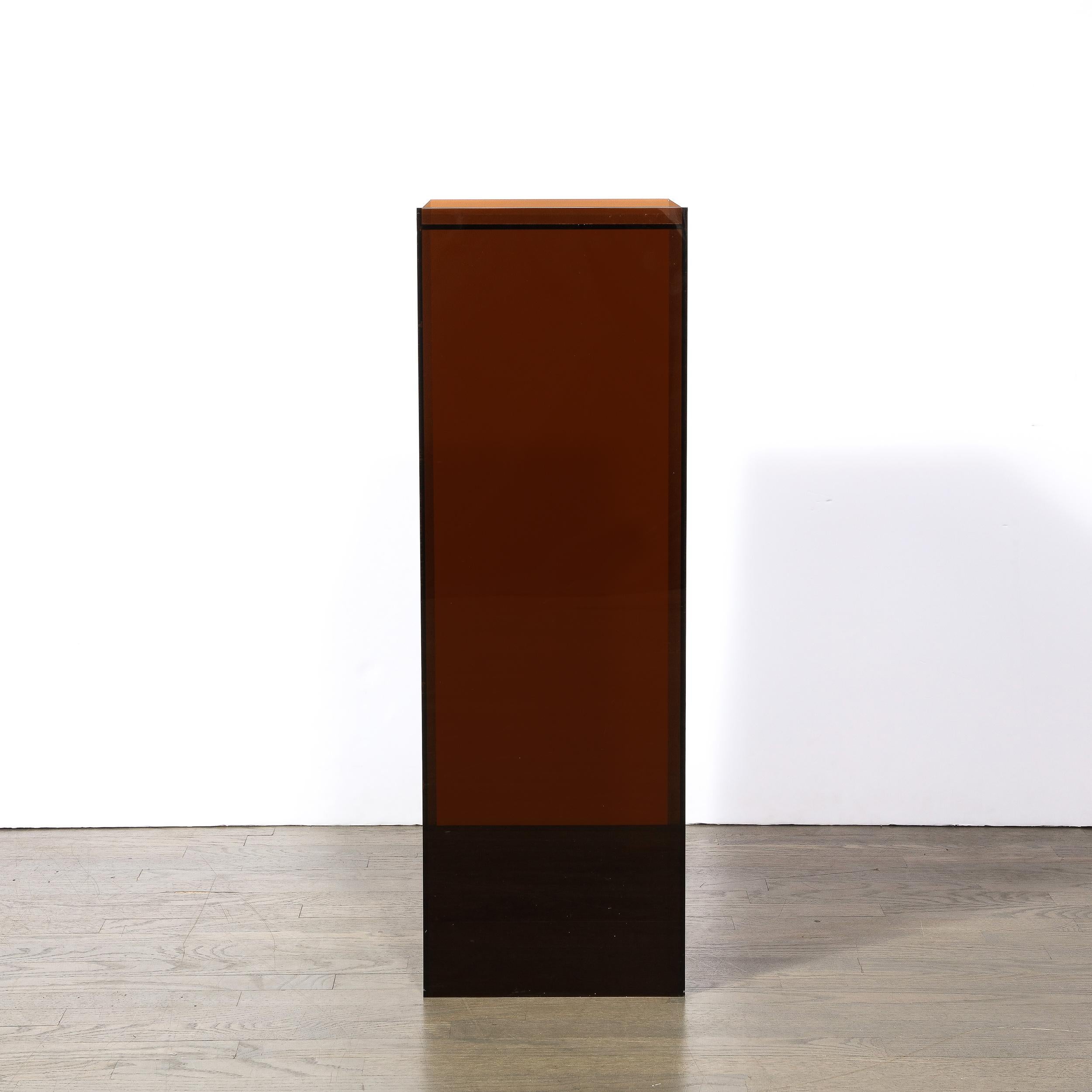 This sophisticated modernist pedestal was realized in the United States circa 1980. It features a volumetric rectangular body with an inset mirror top in a sexy and sumptuous smoked bronze lucite. With its clean modernist lines, this piece is as