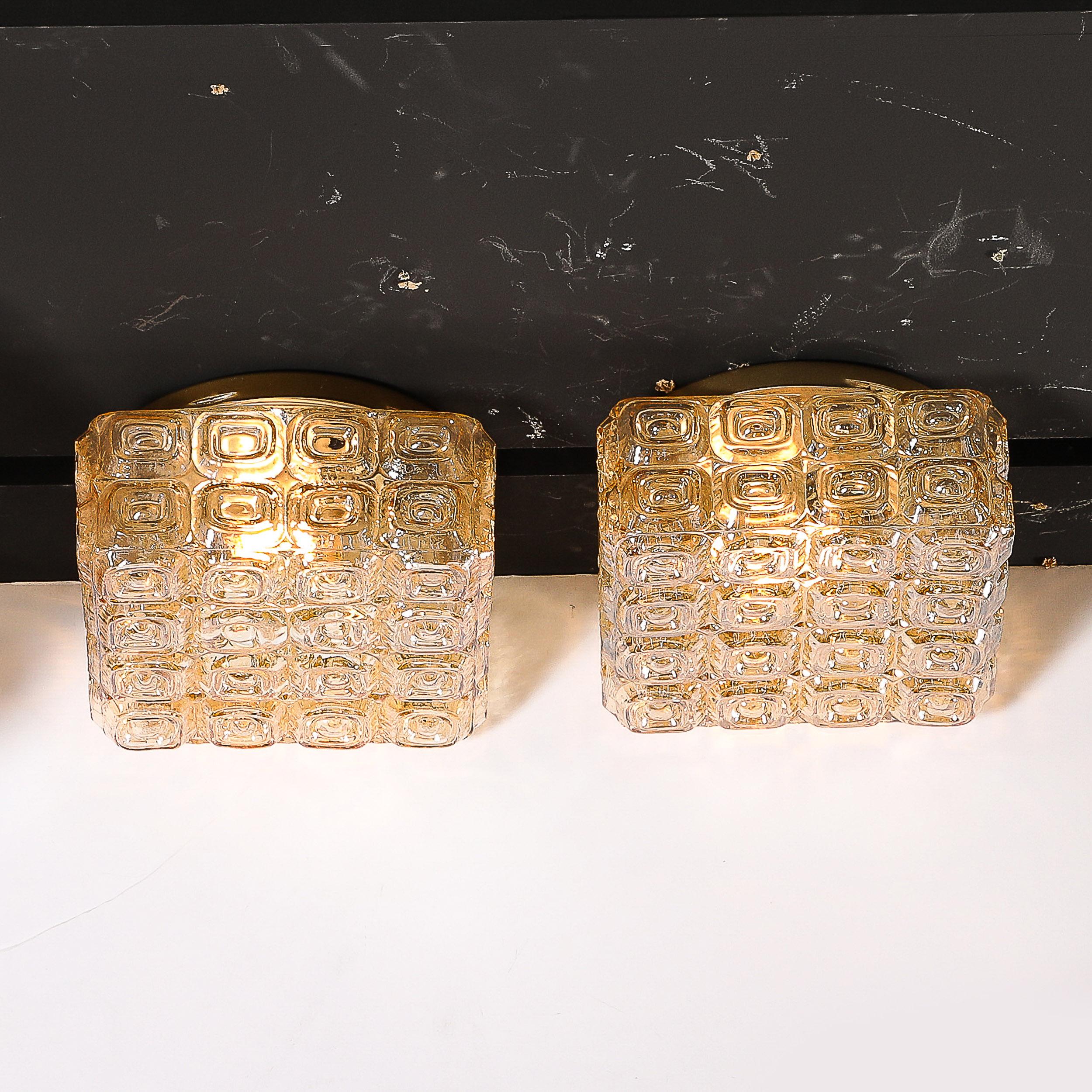 Cette paire de lustres affleurants géométriques en verre ambré pressé, d'un style moderniste du milieu du siècle, est originaire d'Allemagne, vers 1960. Leur design compact à montage encastré est parfait pour les pièces à plafond plus bas, tout en