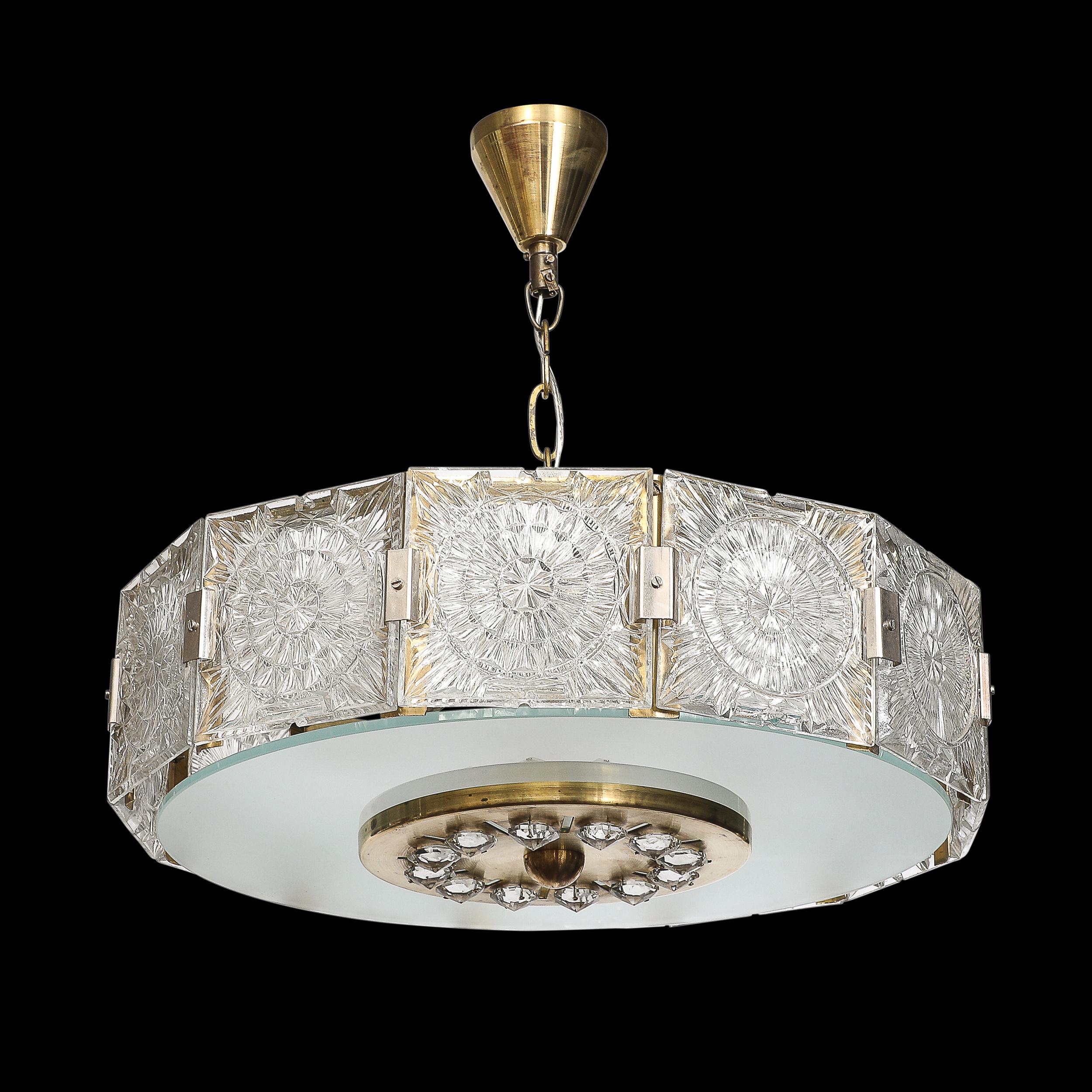 Questo splendido lampadario a sospensione del Mid-Century Modernist è un brillante esempio di design vintage cecoslovacco degli anni '60. Il lampadario è caratterizzato da una struttura in vetro pressato sfaccettato che rifrange la luce in modo
