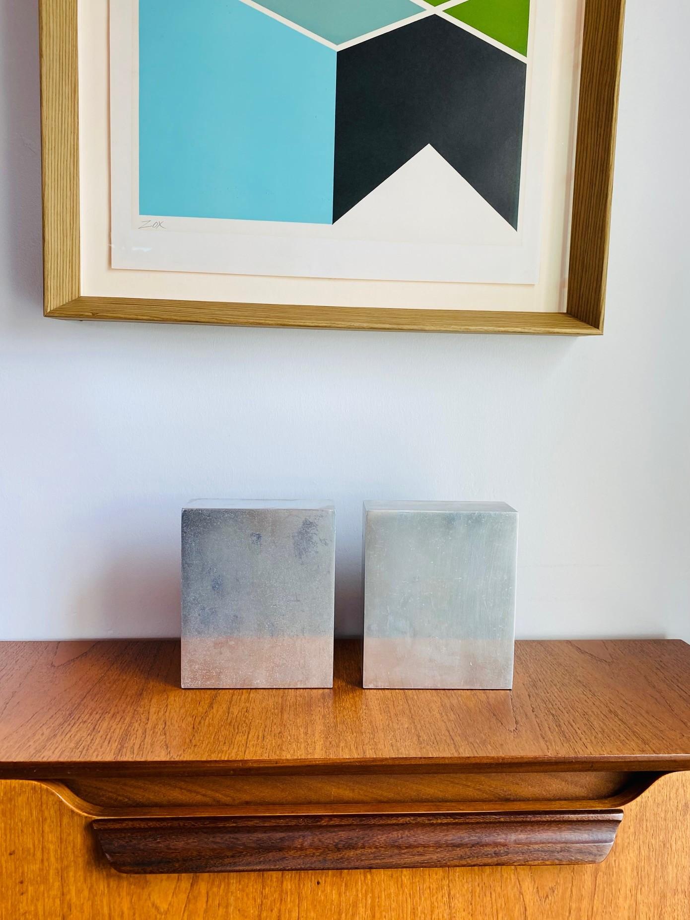 Beautiful pair of modernist chrome bookends by Smith Metal Arts. These sizeable pieces of chrome are captivating as they are commanding. Their styling is simple timeless.  Aged chrome along simple lines bring out the sculptural and minimal to the