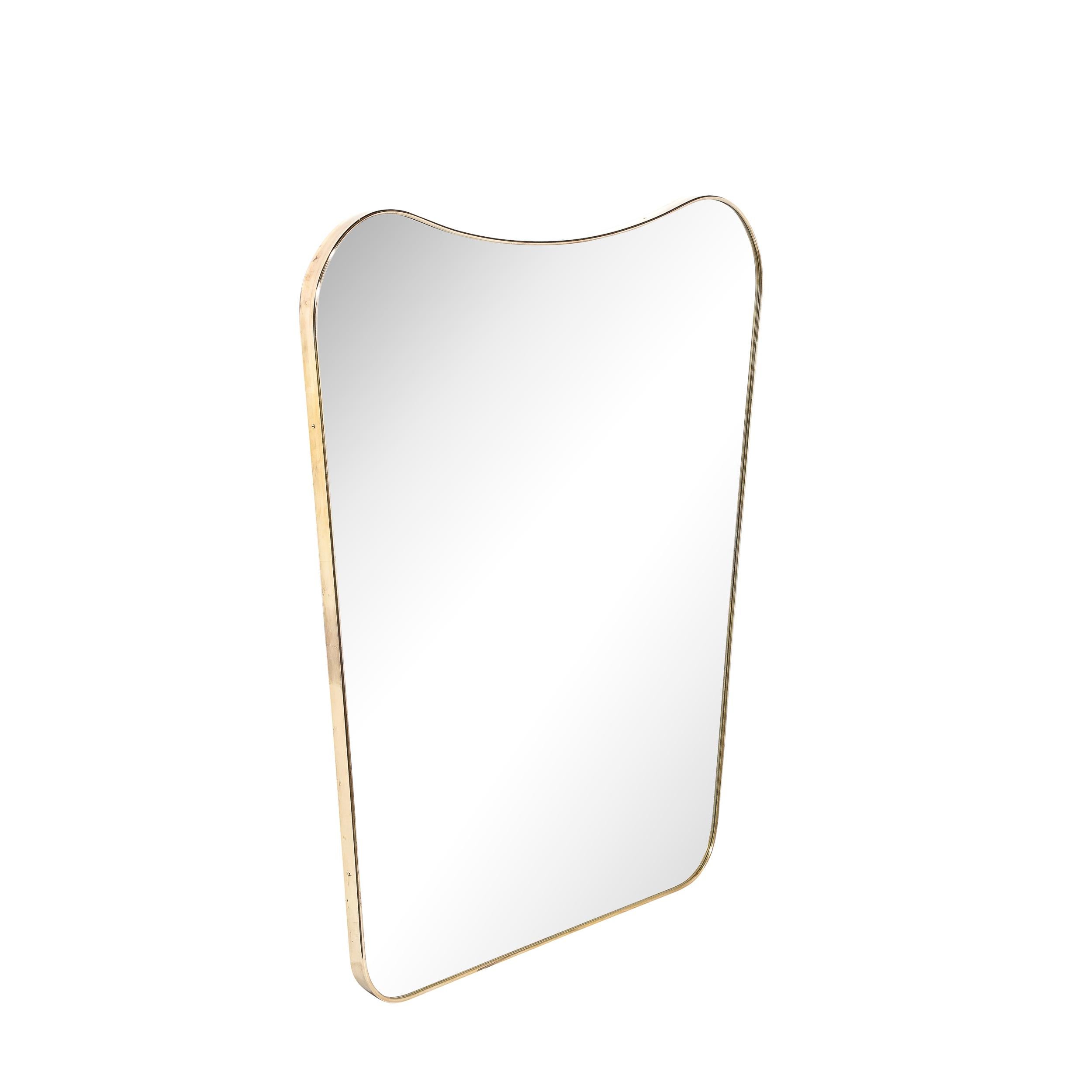 This lovely Mid-Century Modernist Shield Form Polished Brass Wrapped Mirror Originates from Italy, Circa 1950. Features a curvilinear heraldic shield form profile with raised & rounded top corners, well proportioned and rendered in remarkably high