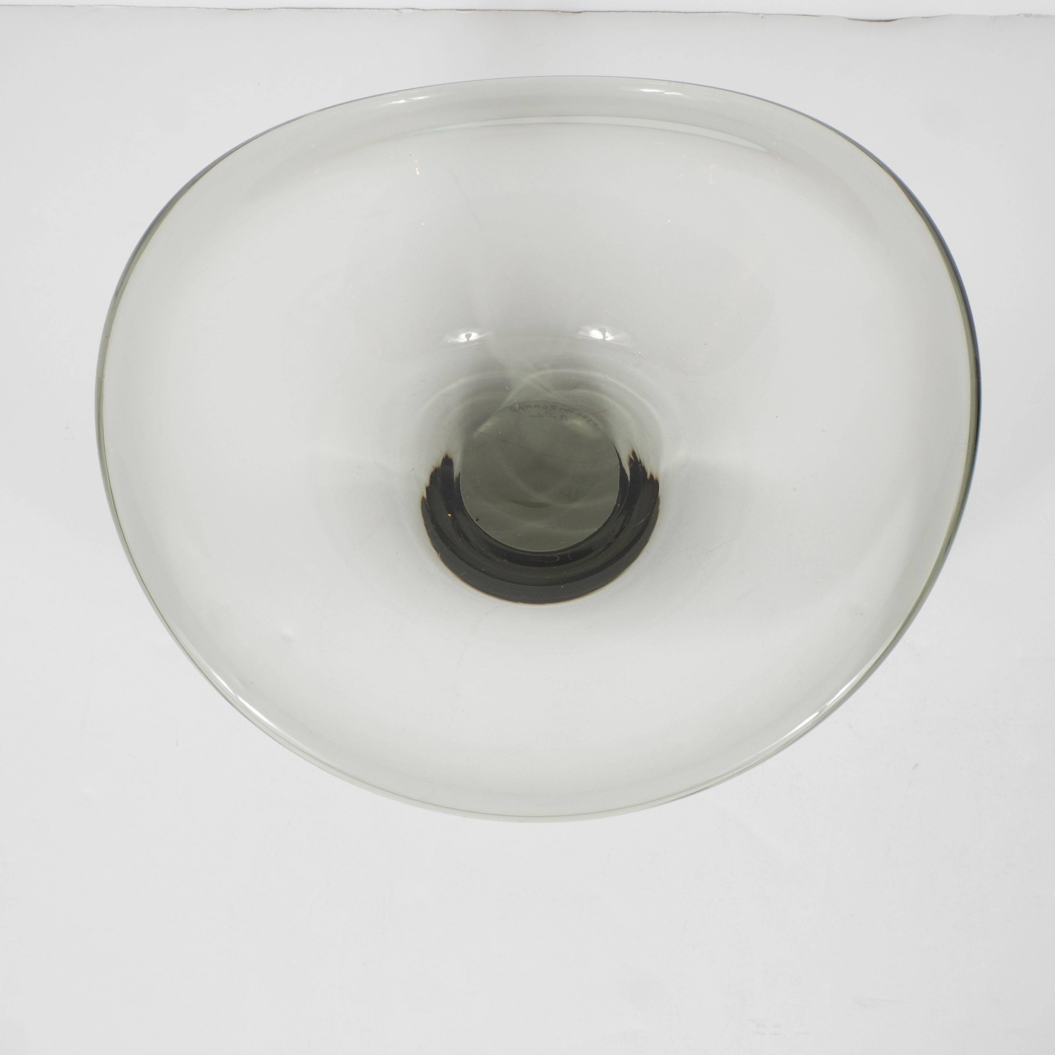 Eine gebogene Rauchglasschale von Holmegaard aus Dänemark aus der Mitte des Jahrhunderts. Der flache Sockel und die runde Form weisen geschwungene, wellenförmige, abgerundete Kanten auf. Handgeblasenes rauchgraues Glas mit Farbabweichungen. Signiert