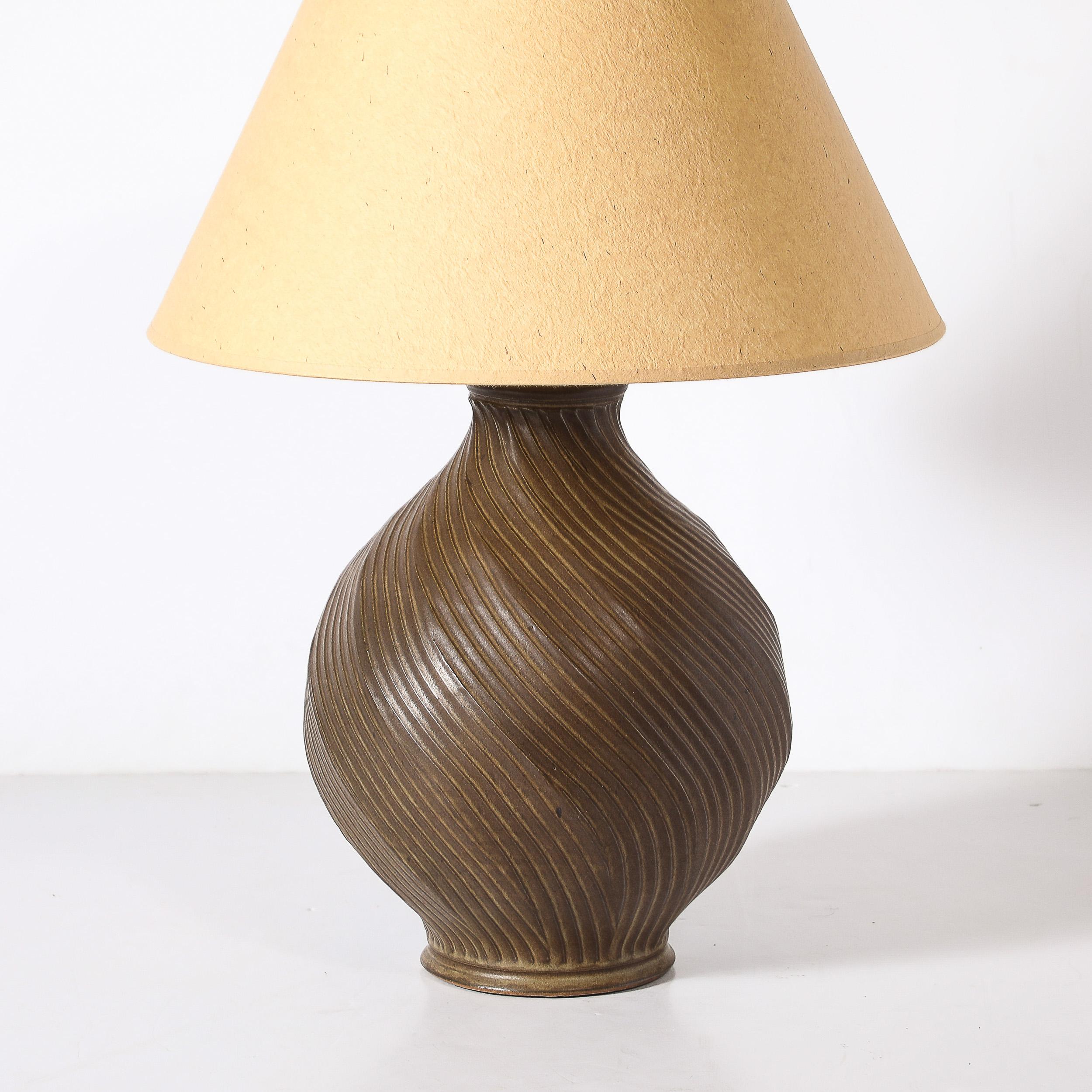 Questa splendida realizzazione  La lampada da tavolo con scanalatura a spirale in ceramica color umido bruciato è originaria degli Stati Uniti, circa 1960. Caratterizzato da una silhouette classica con un dettaglio scanalato e una base e un collo