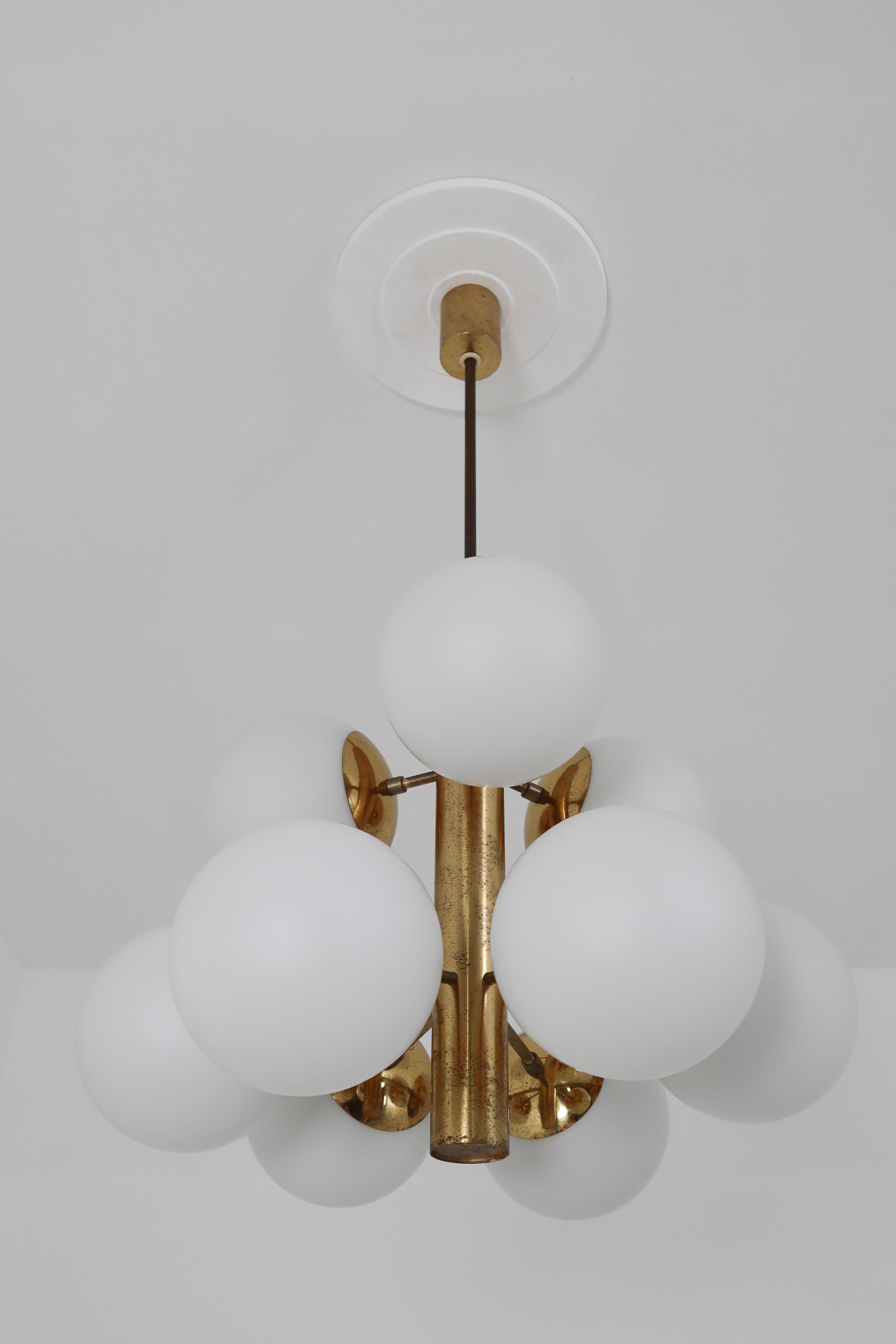 This fantastic Mid-Century Modernist Sputnik chandelier was designed in Germany 1960s featuring a patinated brass frame and nine handblown opal glass globes.