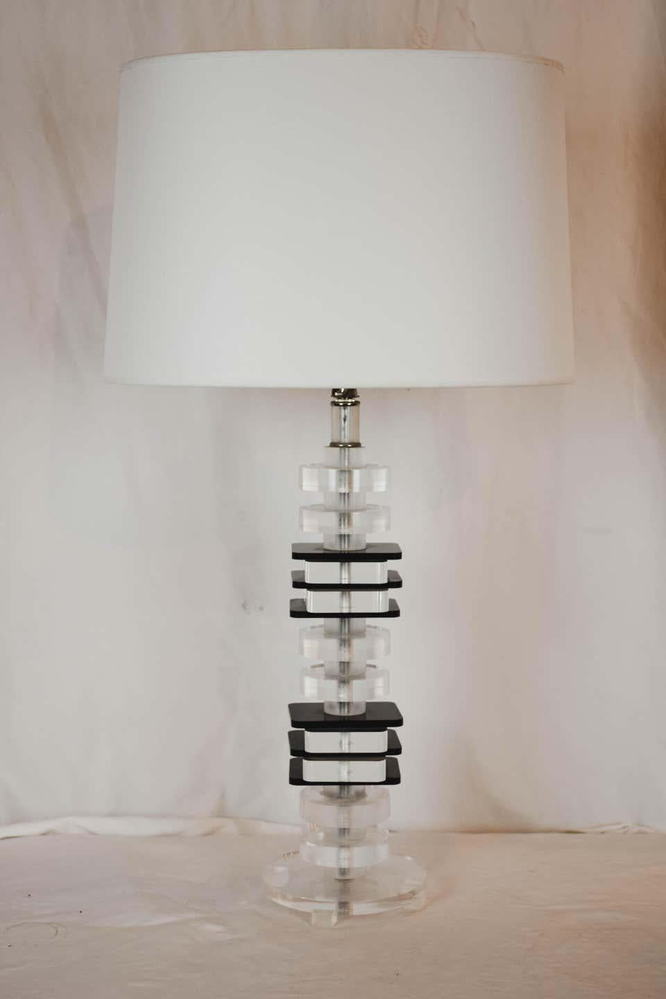 A Mid-Century Modernist lamp featuring contrasting black and clear Lucite squares. Each Lucite square is stacked in alternating clear and black and rest on a clear Lucite base. This lamp measures: 29.5