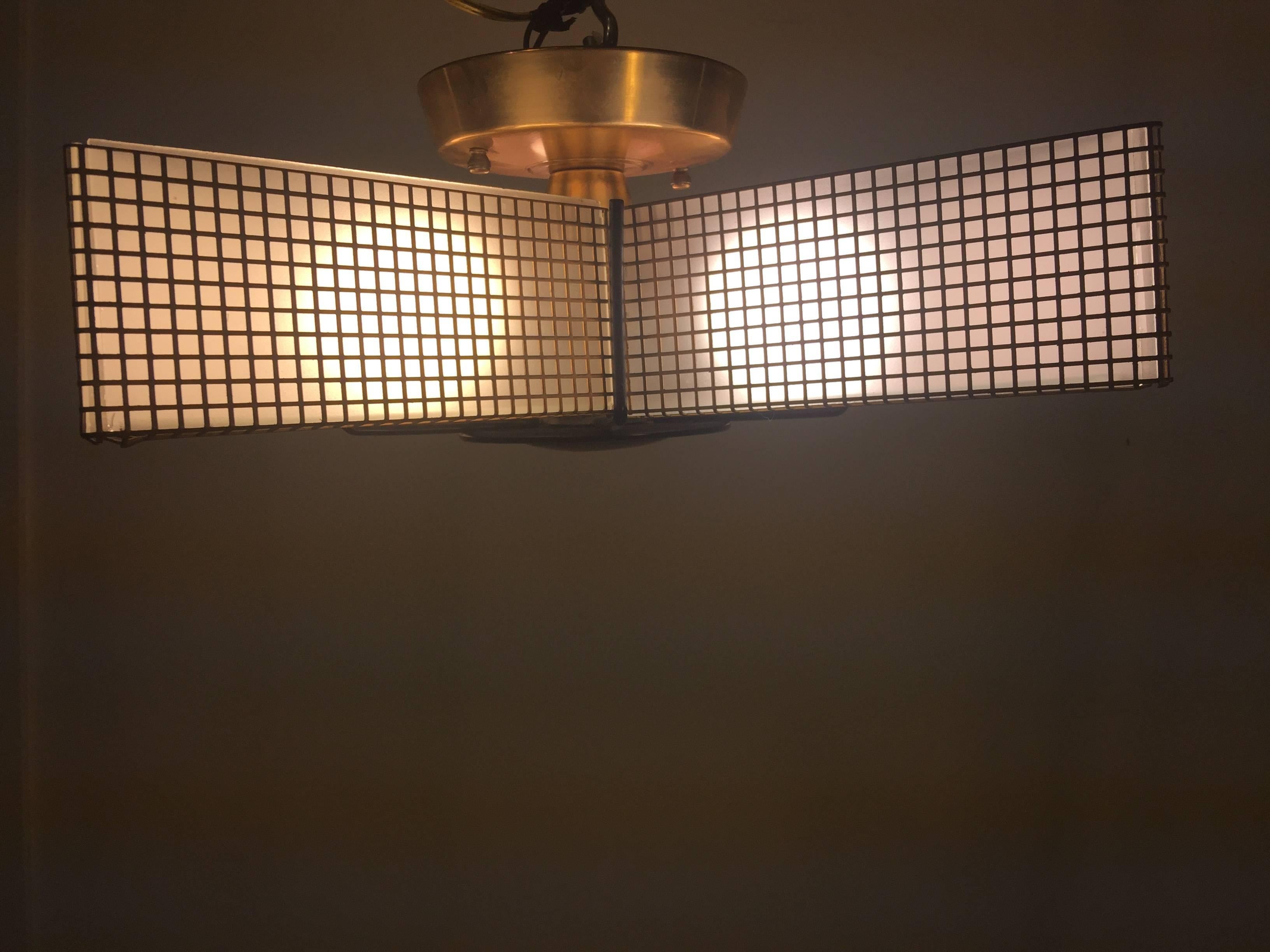 Midcentury star chandelier comprised of brass square design mesh frame and black enameled brass bulls eye centre with radiating lines that form the bottom of the chandelier. White geometric design etched glass panels are set within the five arms