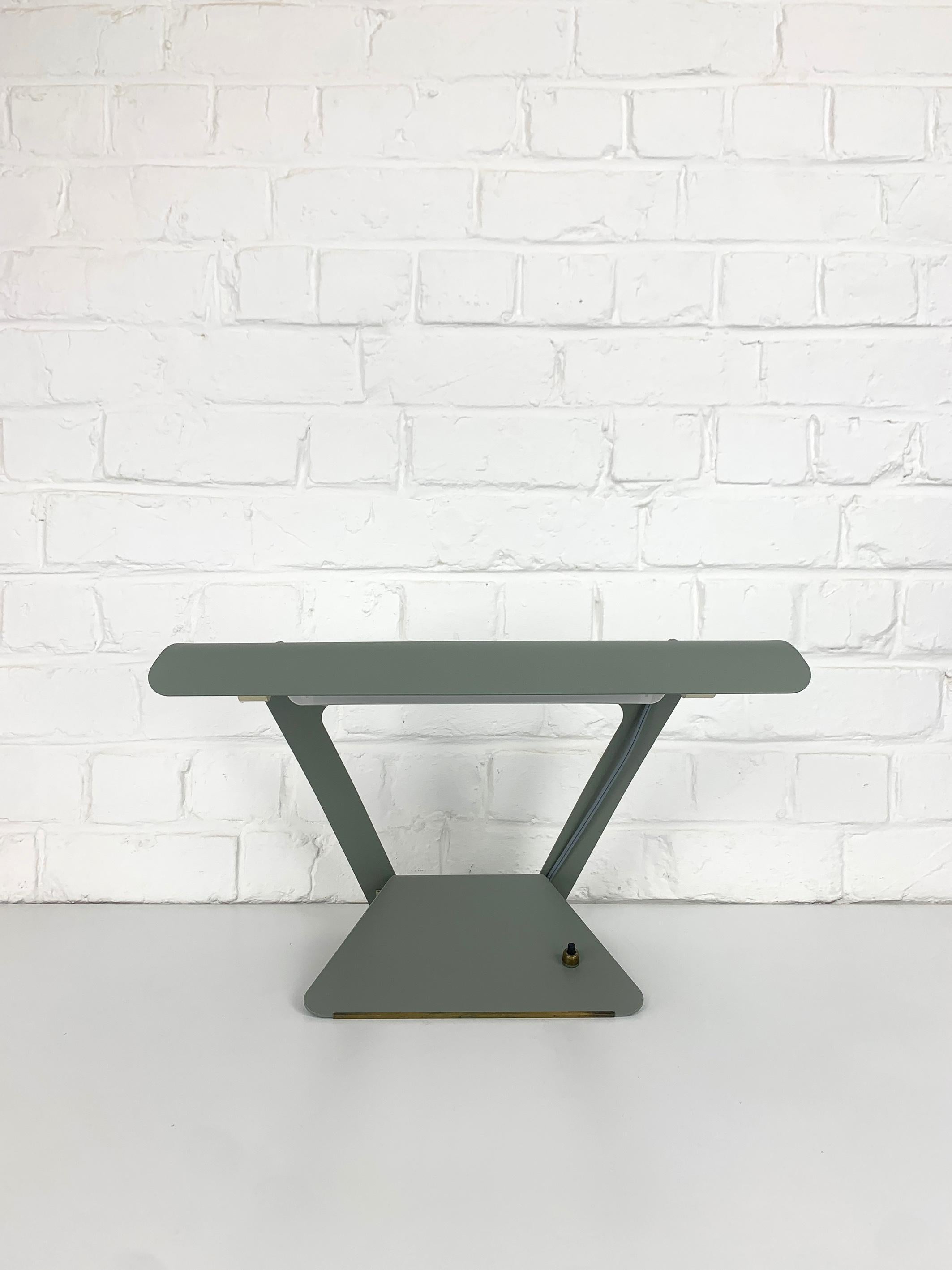 Lampada da scrivania modernista realizzata con un unico foglio di metallo tagliato e piegato, una soluzione di design molto innovativa immaginata da Charlotte Perriand per Philips. 

Questa lampada utilizza una speciale lampadina tubolare a