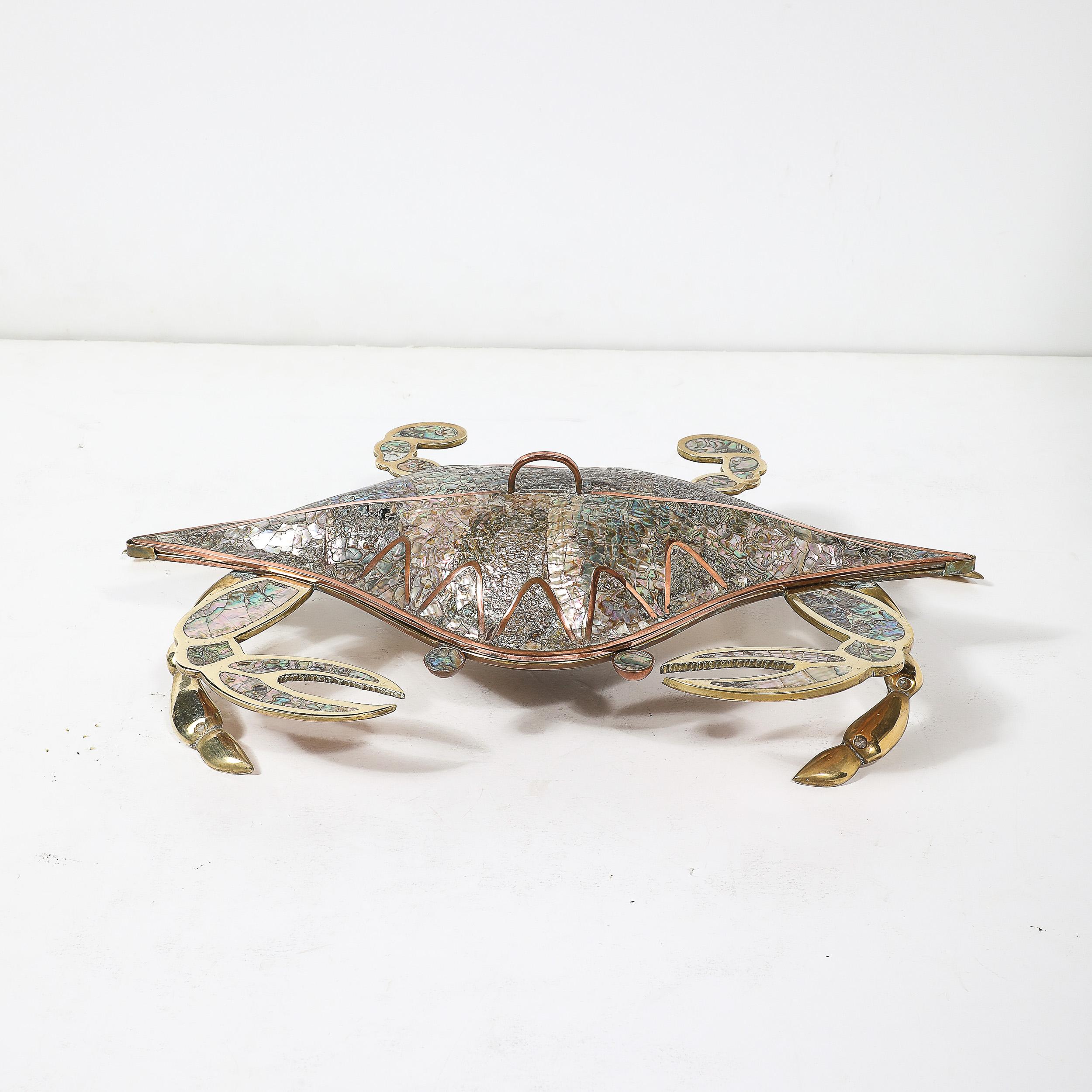 Cette captivante boîte à crabe moderne du milieu du siècle présente un mélange magistral de matériaux naturels et de design artistique. La surface est méticuleusement tessellée de coquilles d'ormeaux irisées, créant une mosaïque chatoyante qui