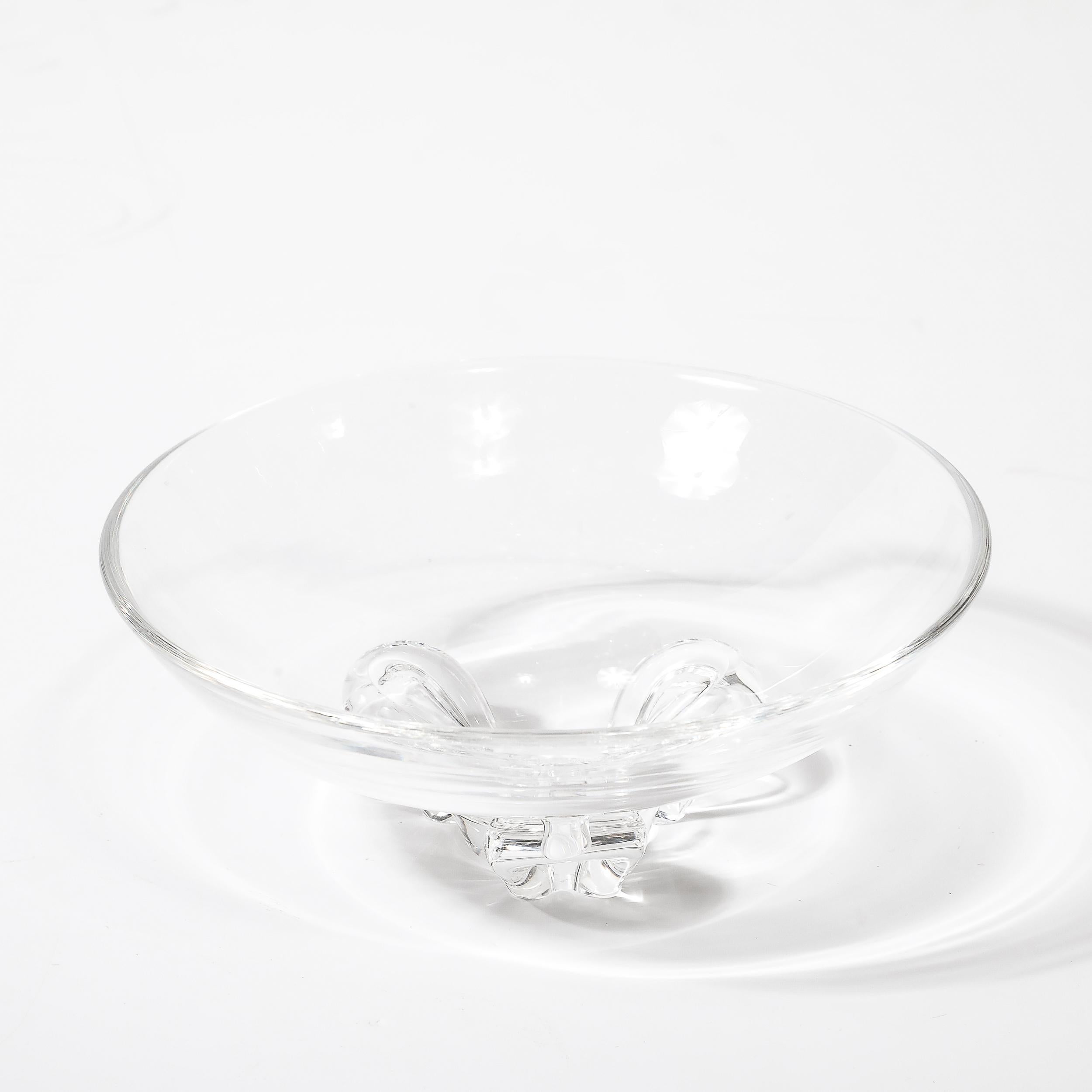 This beautiful Mid-Century Modernist Three Footed Crystal Bowl by Steuben originates from the United States, Circa 1960. This piece is by the esteemed art glass company Steuben, known for their elegant designs and rendered in the highest quality