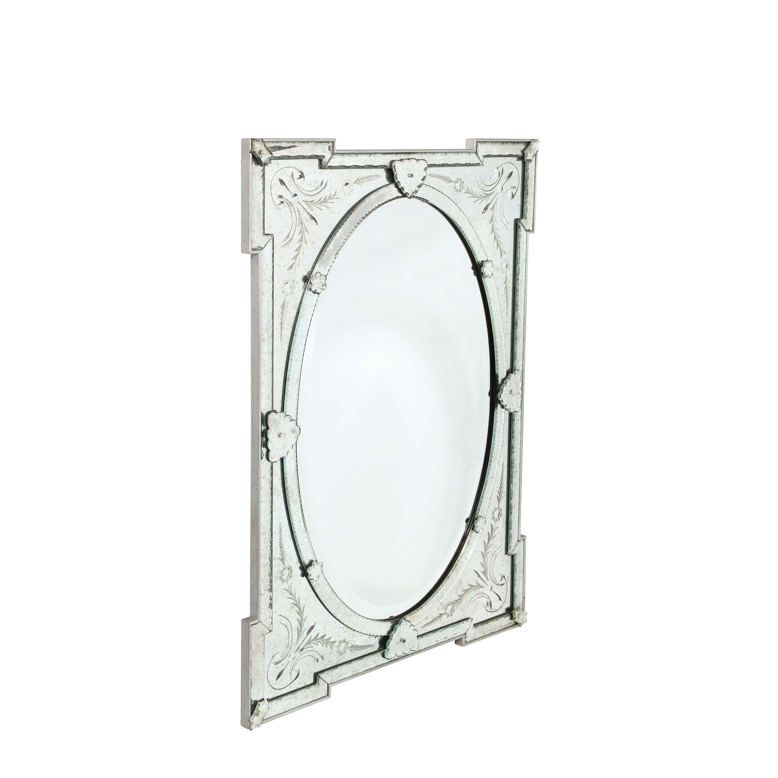 This Mid-Century Modernist Venetian Glass Mirror originates from Italy, Circa 1950. Featuring expanded geometric corners creating space for reversed etched naturalist detailing, the central oval of beveled mirror glass is beautifully proportioned