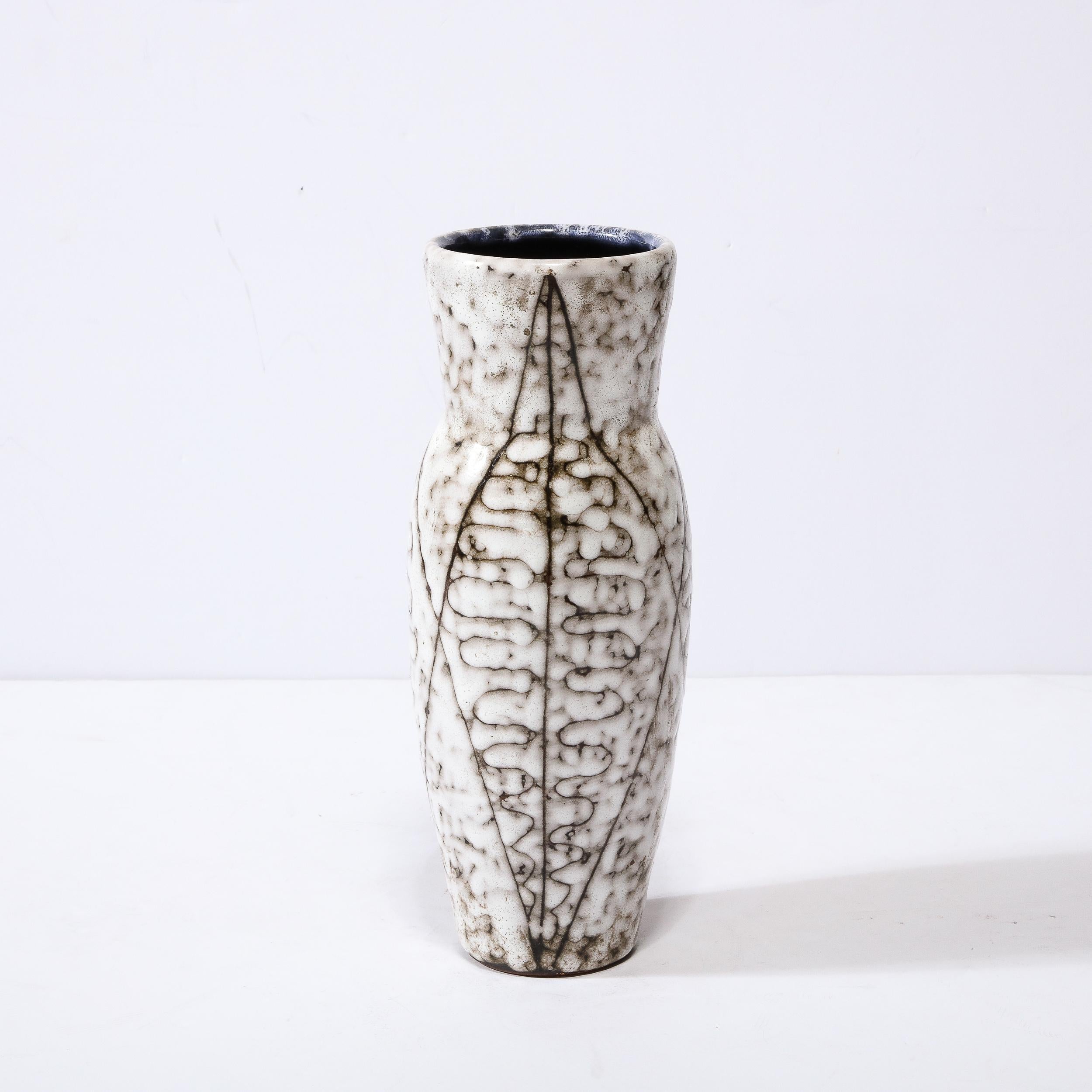This Mid-Century Modernist White and Earth Toned Ceramic Vase With Leaf Motif is a beautiful example of Post War European Ceramics, realized in Hódmezovasarhely Majolikagyár, Hungary circa 1960. With a Stunning textural finish composed in Cream