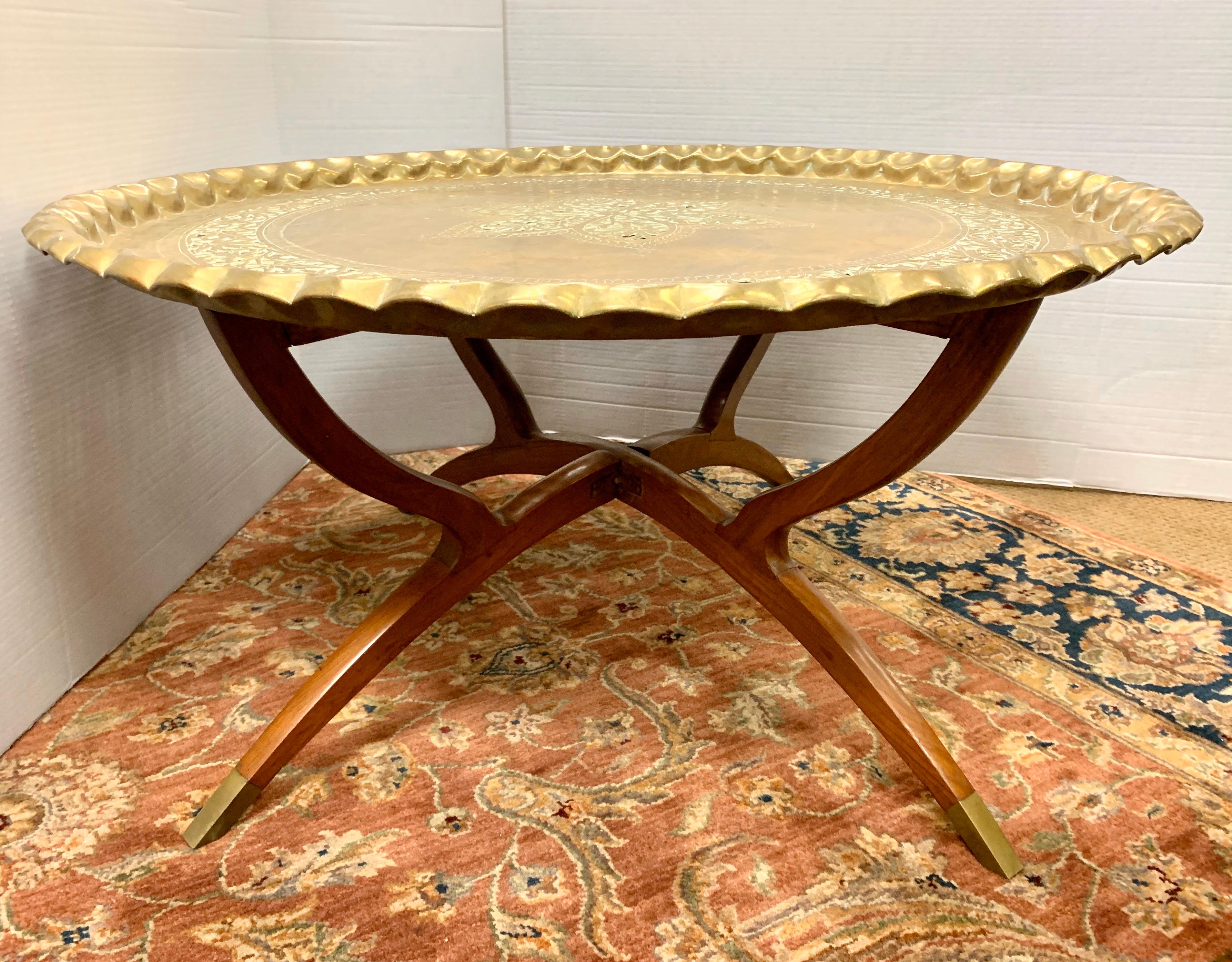 Round hammered Moroccan thirty-six inch brass tray with pierced center star motif and a pierced foliate border. Rest on a folding mahogany stand that features brass feet.
