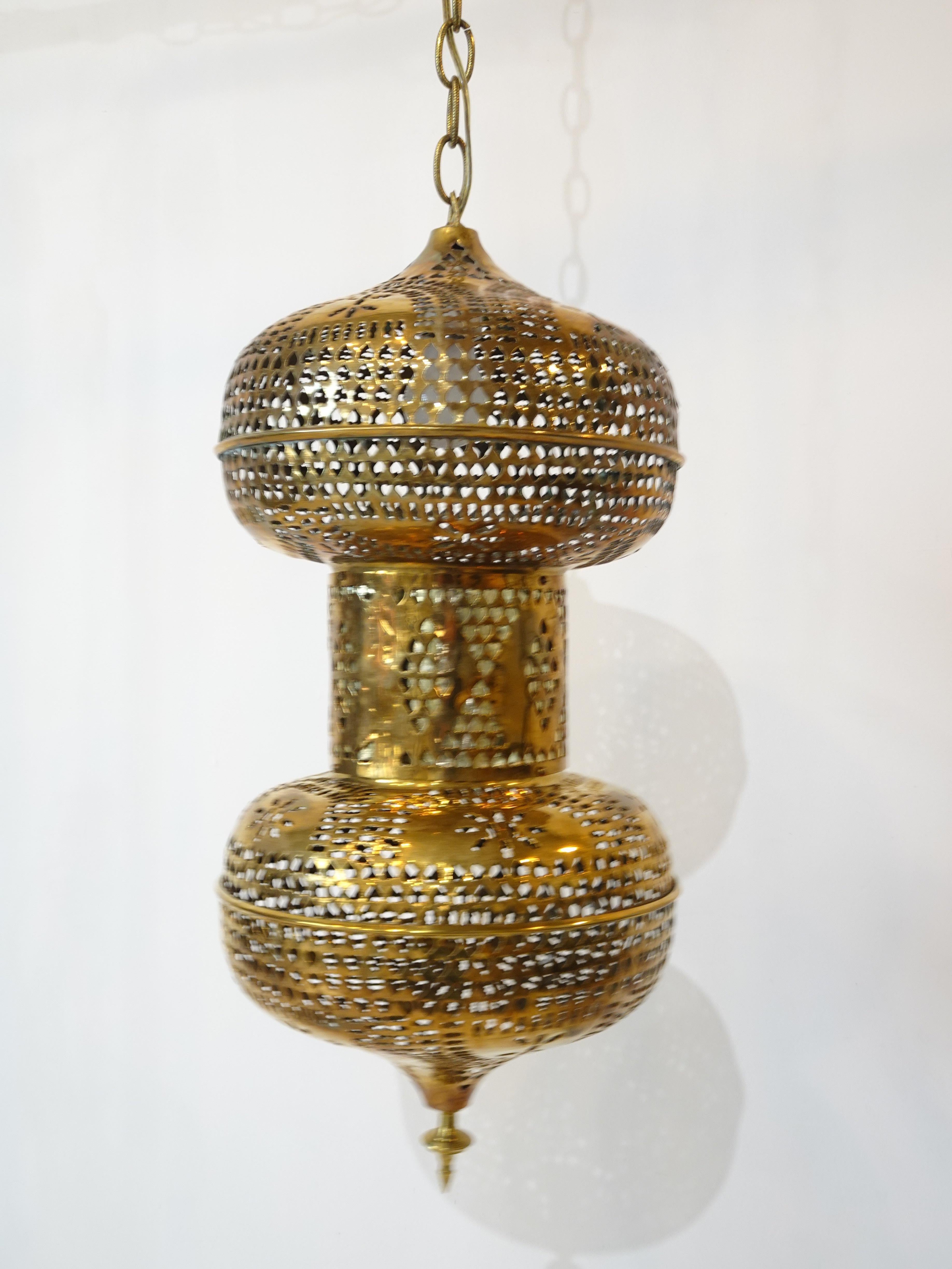 A very Mid Century styled Moroccan Moorish styled hanging brass lamp with cutout perforated construction having 15' of brass chain with great hash mark details to the links. There's two switches for the light one that's near the plug area and one