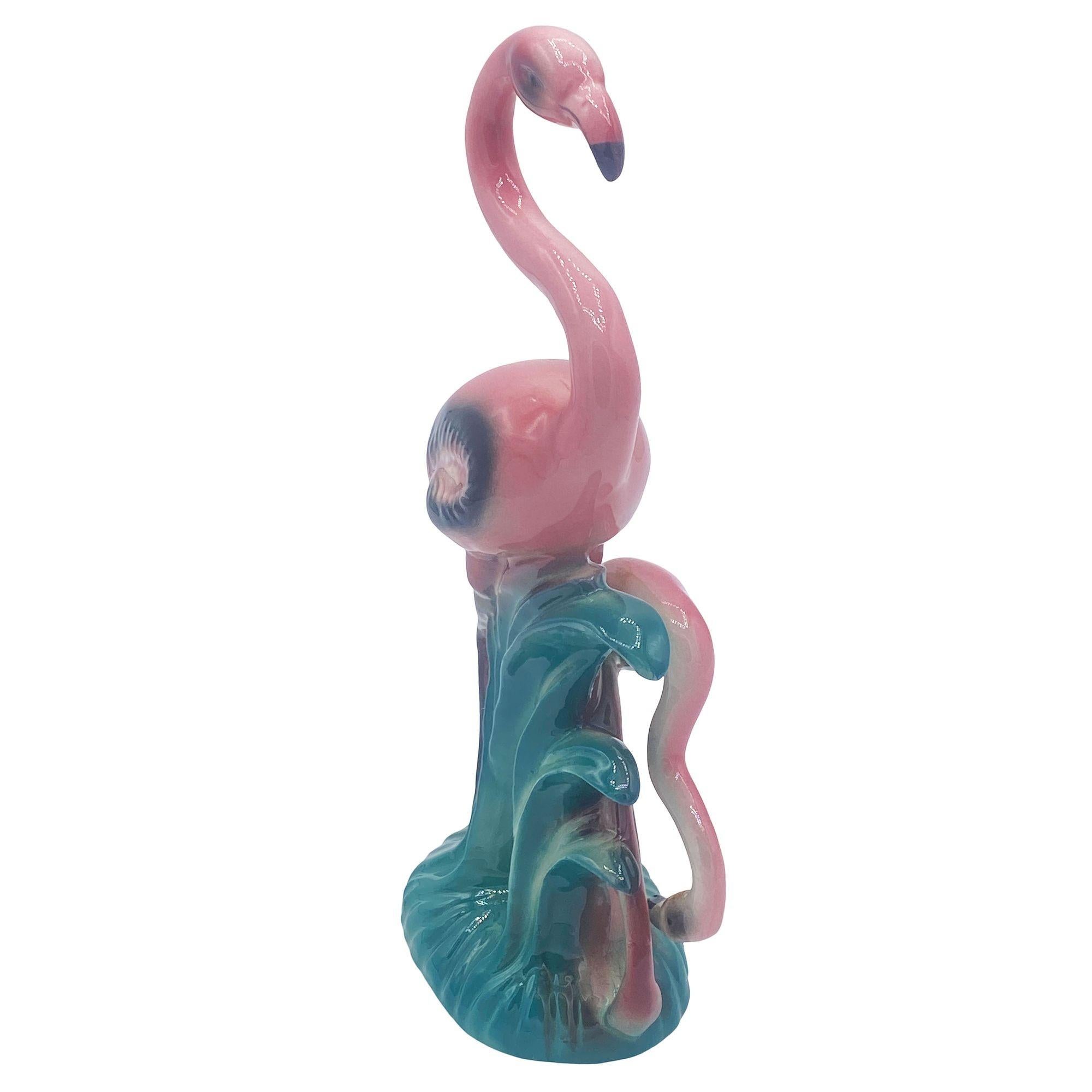 Mid-century pink and green ceramic flamingo tabletop pottery statue by Leftons. The statue features a beautifully detailed pink mother flamingo standing on a grassy field with daughter. It comes in a gloss finish that highlights the rich pinks,