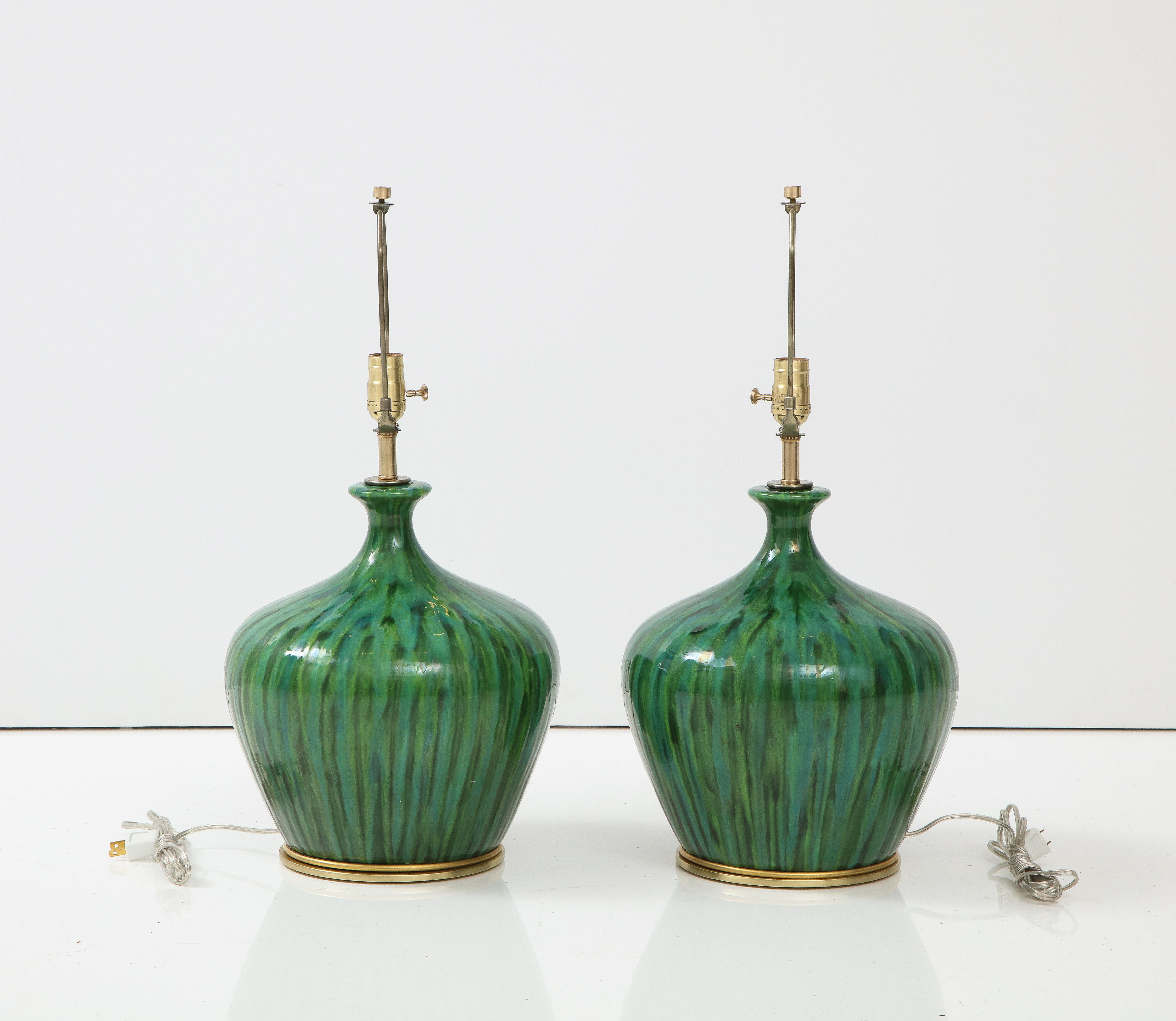 Modernist pair of mottled / striated emerald green glazed porcelain lamps sitting on custom aged brass disc bases. Rewired for use in the USA, 100W max.