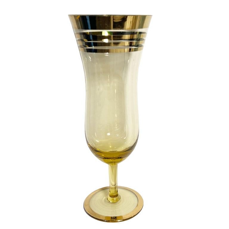 A set of six Mid-century tall multicolor hurricane glasses with gold accents. This set of six will make a wonderful addition to your barware. The set includes two blue, one green, one amber, one purple, and one in gray-brown. Each glass has a curvy