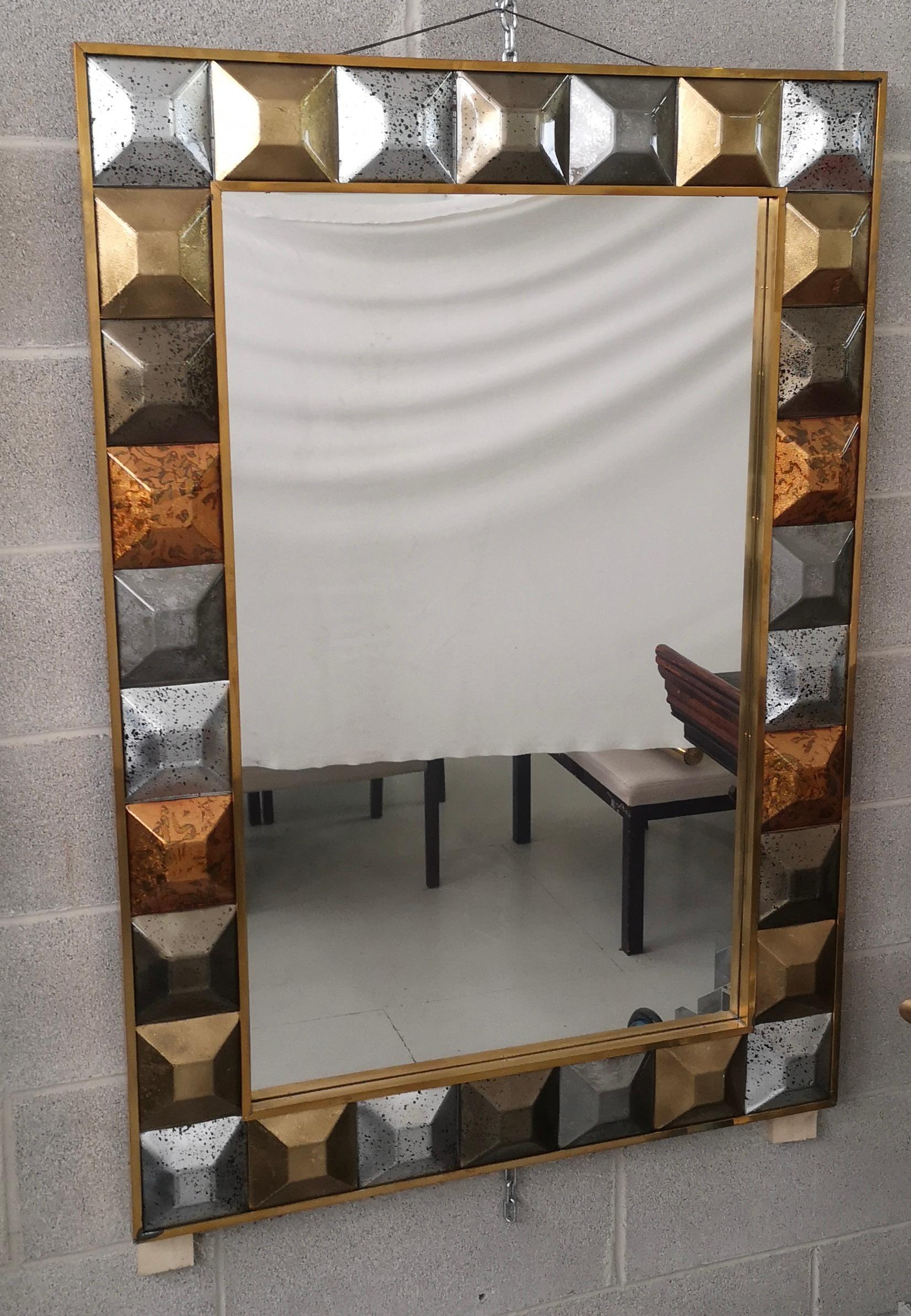 A strong brass color frame reach the eye of the beholder leaving him entranced; of Murano multi color art glass wall mirror. 

The structure of the wall mirror is in wood, where the multi color Murano glass is housed. The frame of the mirror is made