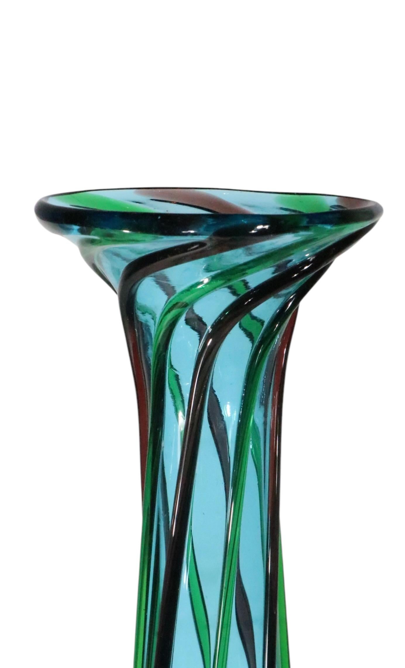 Eccezionale vaso in vetro artistico, con collo allungato e base a forma di palla. Il fondo azzurro è decorato in verticale.  vetro verde e viola  fili. 
 Realizzato a Murano, circa 1950/70, attribuito a Seguso, non firmato. 
 H. H. totale 17
