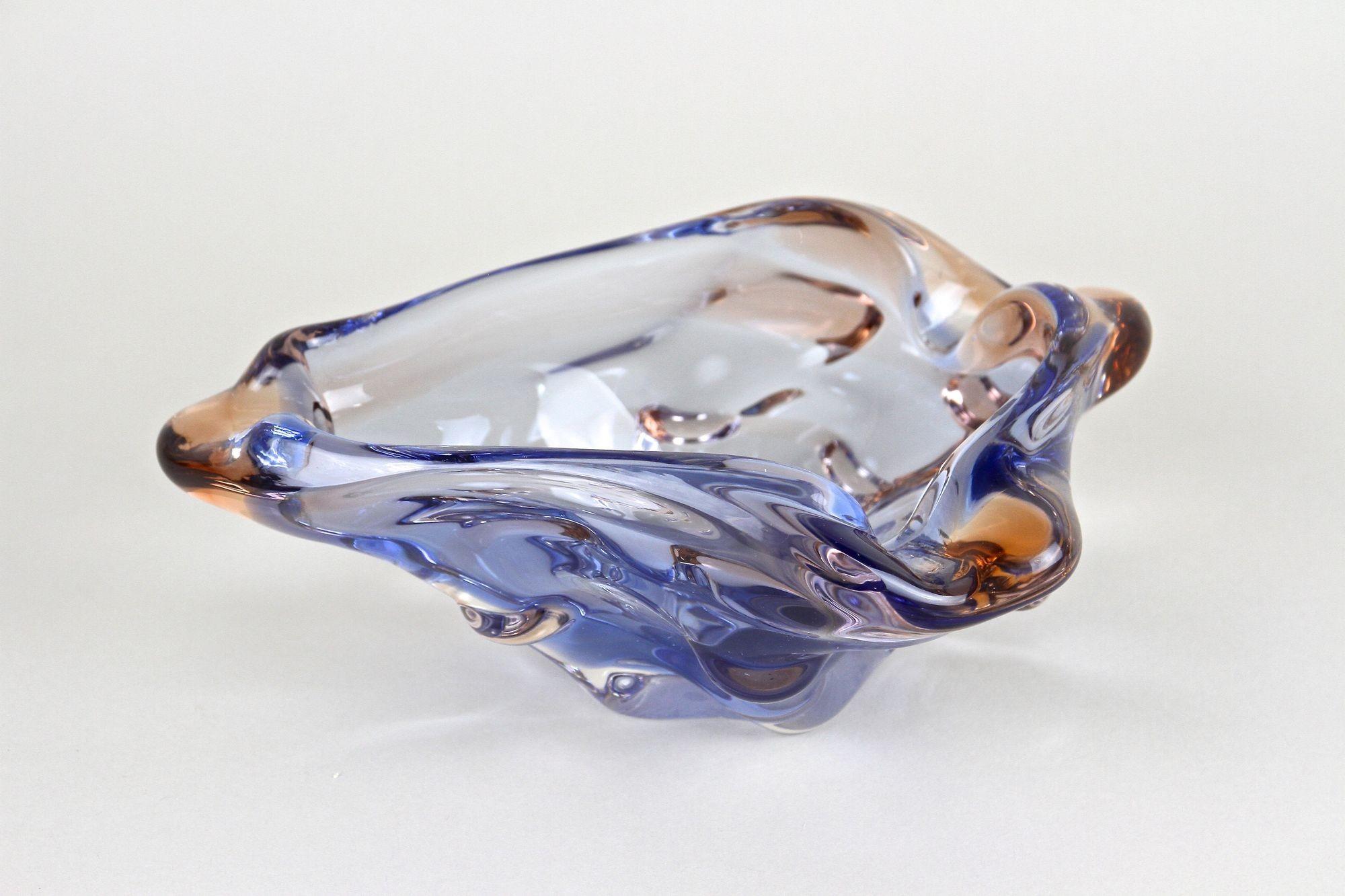 Extraordinary small Murano glass bowl coming from the famous workshops in Italy from the period around 1960/70. Colored in a fantastic blue and amber tone, this amazing designed, contemporary glass bowl impresses with its unusual shaped body - just